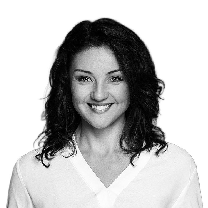 A black-and-white portrait of a smiling woman with wavy dark hair wearing a white top.
