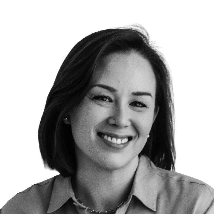 Black and white portrait of a woman with shoulder-length hair, smiling, wearing a leather jacket