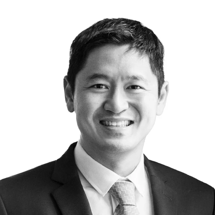 Black-and-white portrait of a smiling man wearing a suit, white shirt, and tie.