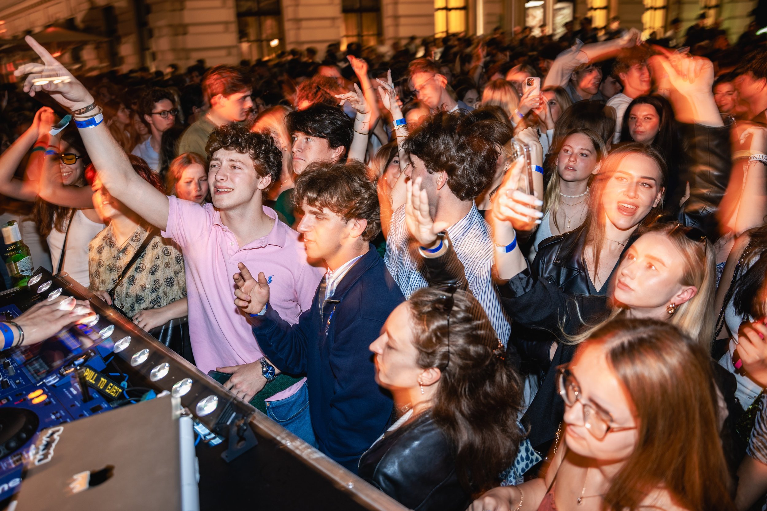 Crowd of people dancing and enjoying music at an outdoor event at night.