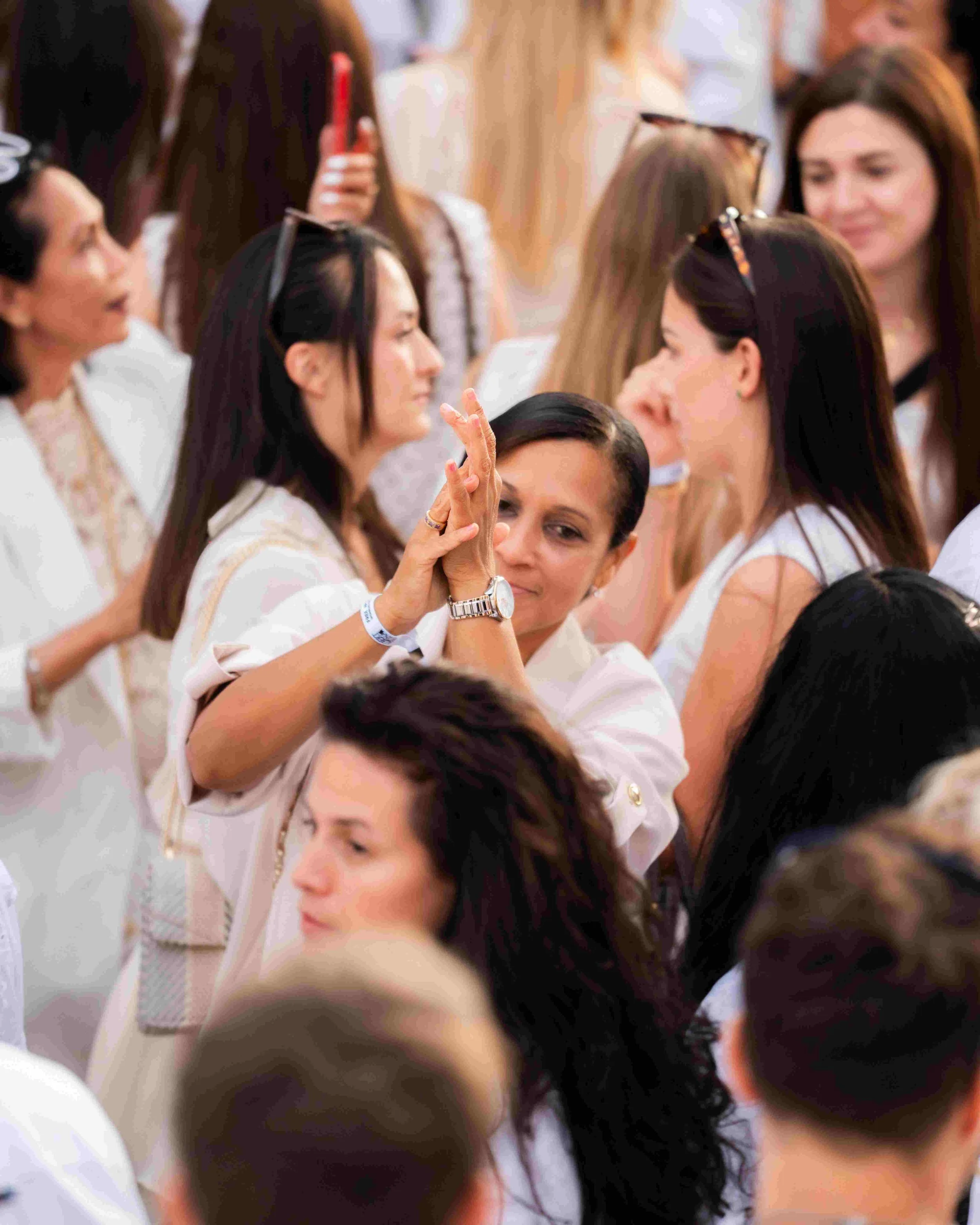 Group of women engaging in a cultural or spiritual ceremony, with some women having their hands raised and in prayer or greeting poses.