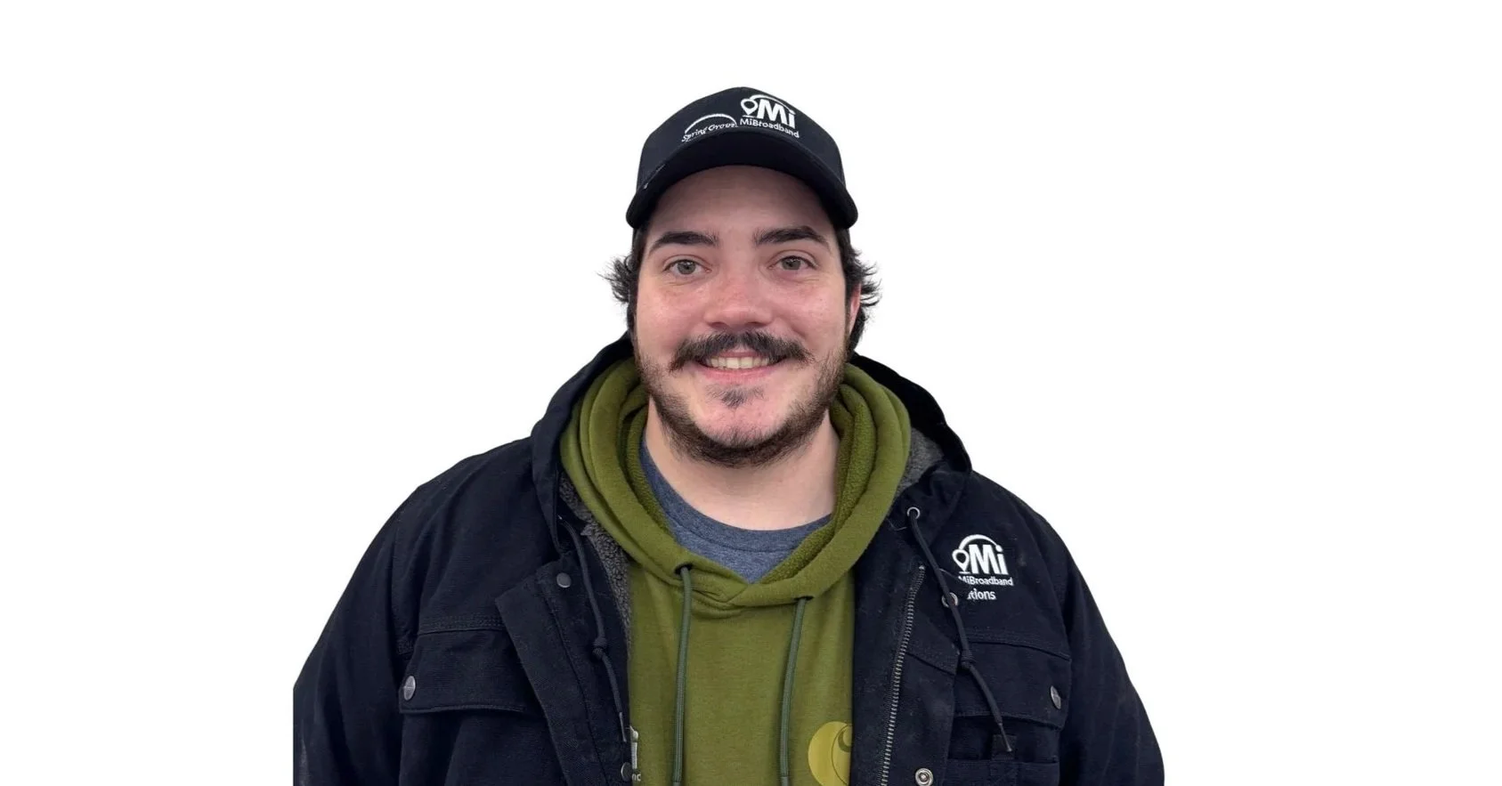 Smiling man wearing a black jacket and green hoodie, with a black baseball cap, against a plain white background.