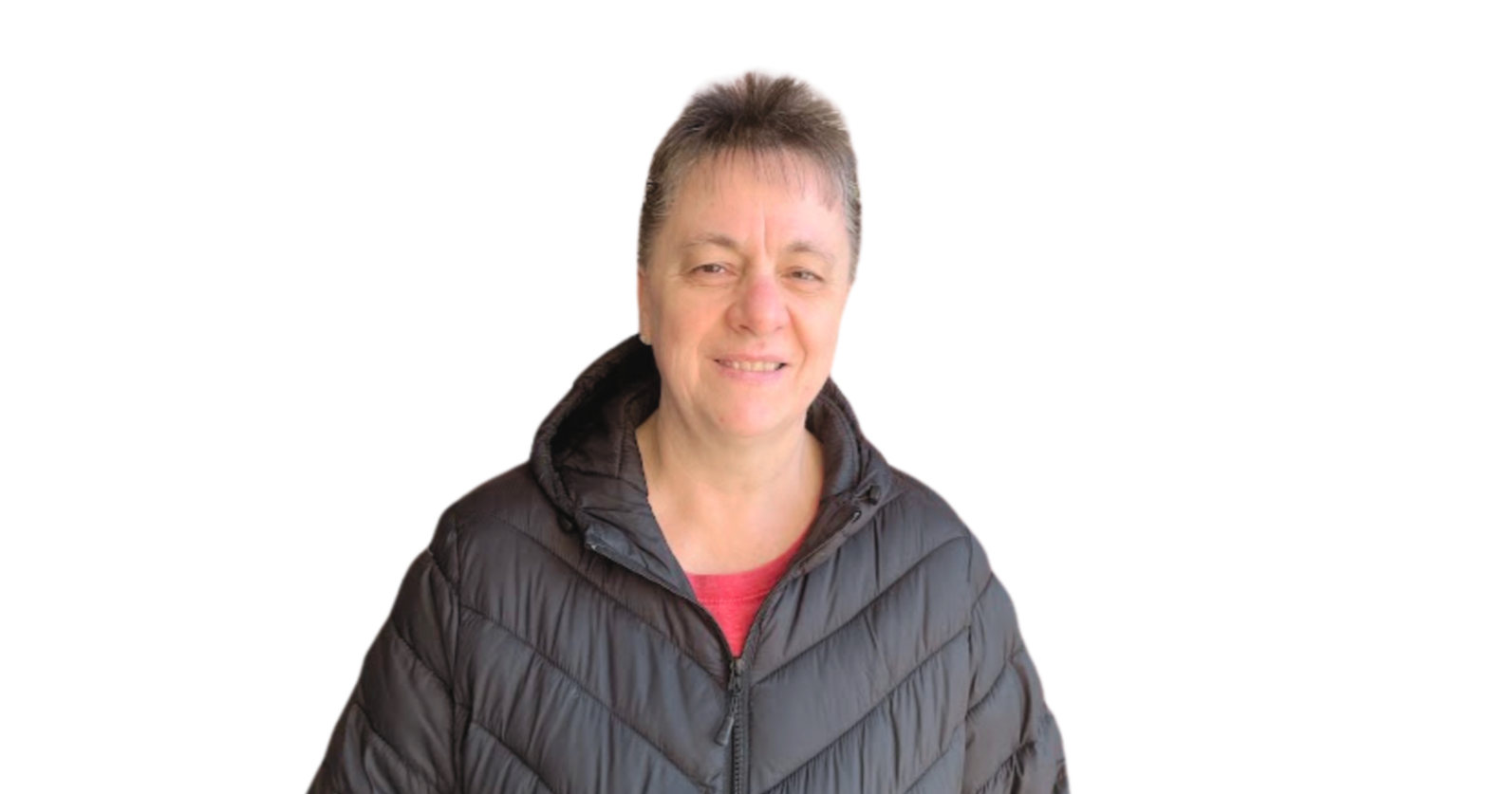 A woman with short gray hair wearing a black puffer jacket and a red shirt, smiling at the camera against a plain white background.