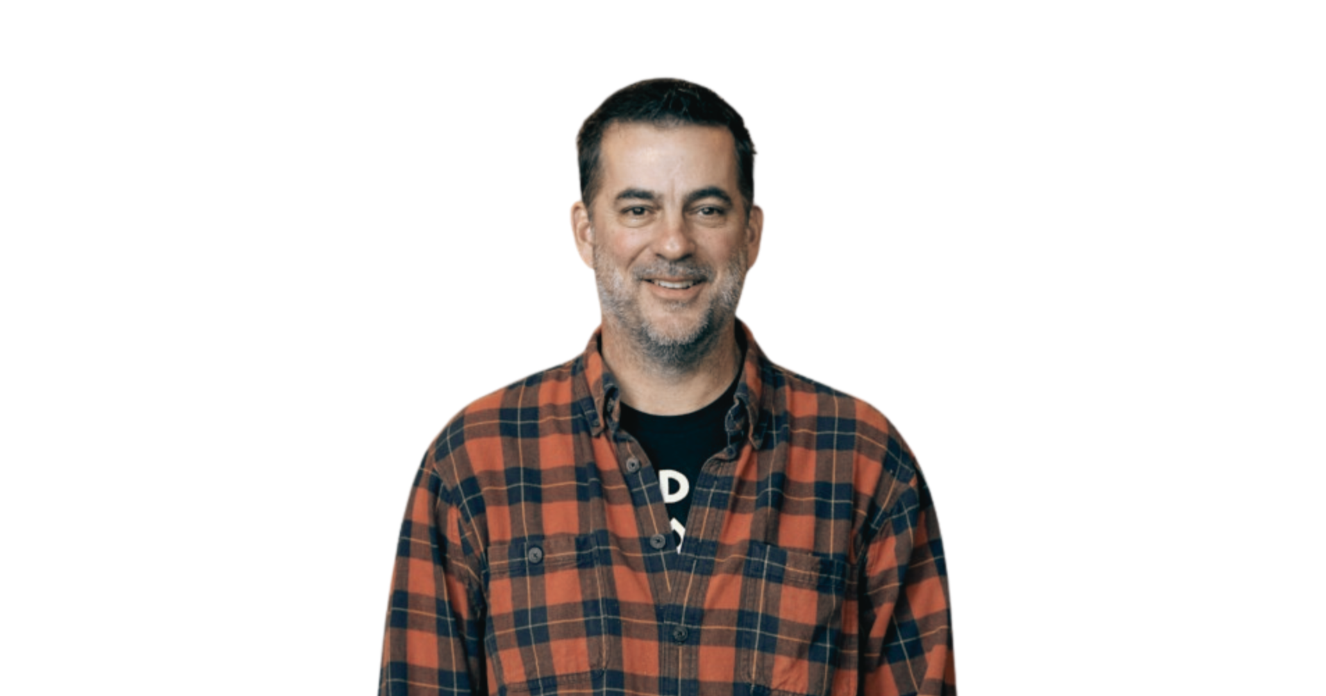 Smiling man with dark hair, beard, wearing a plaid shirt over a black t-shirt, isolated on white background.