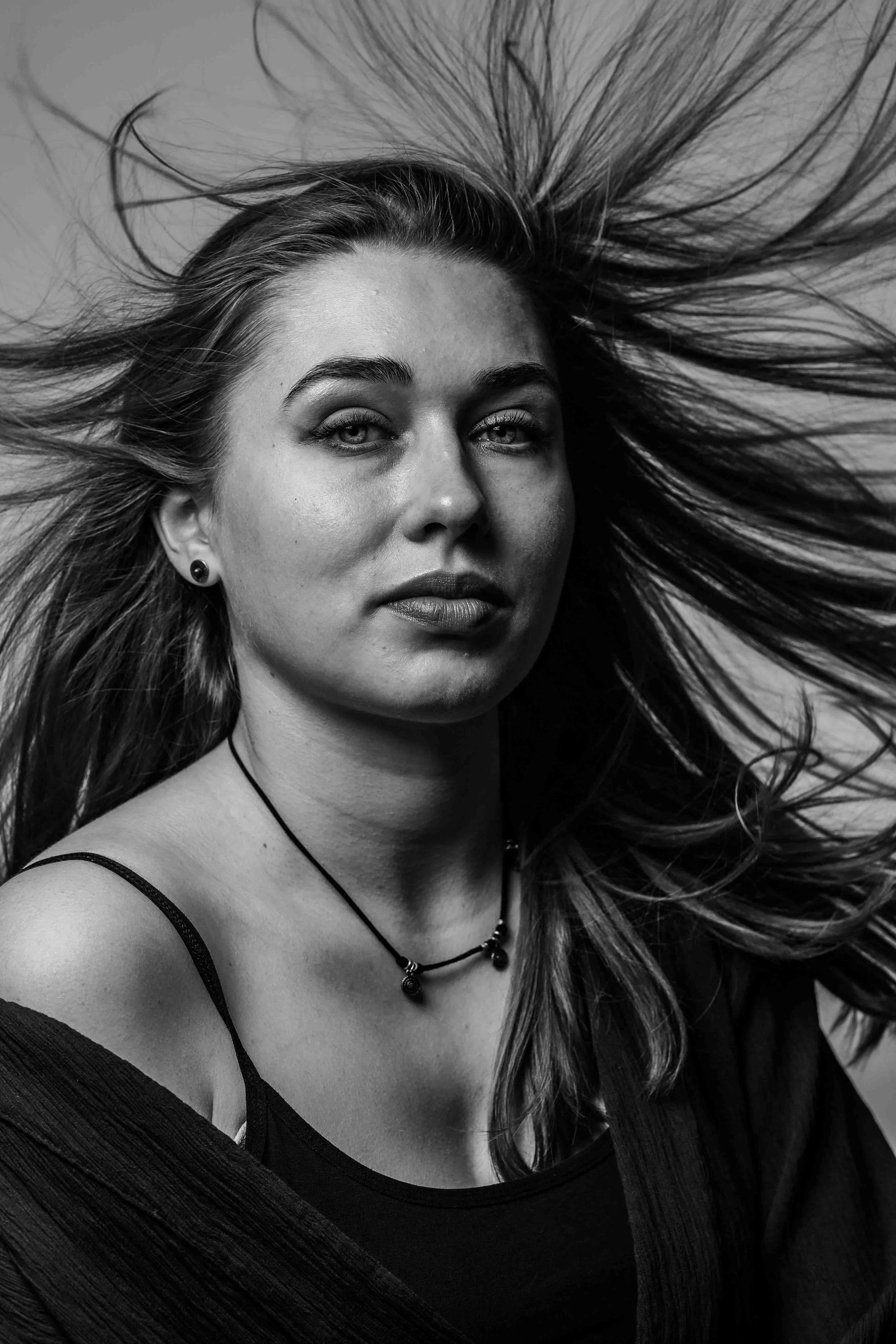 Zwart-wit foto van een vrouw met lang haar die naar de camera kijkt.