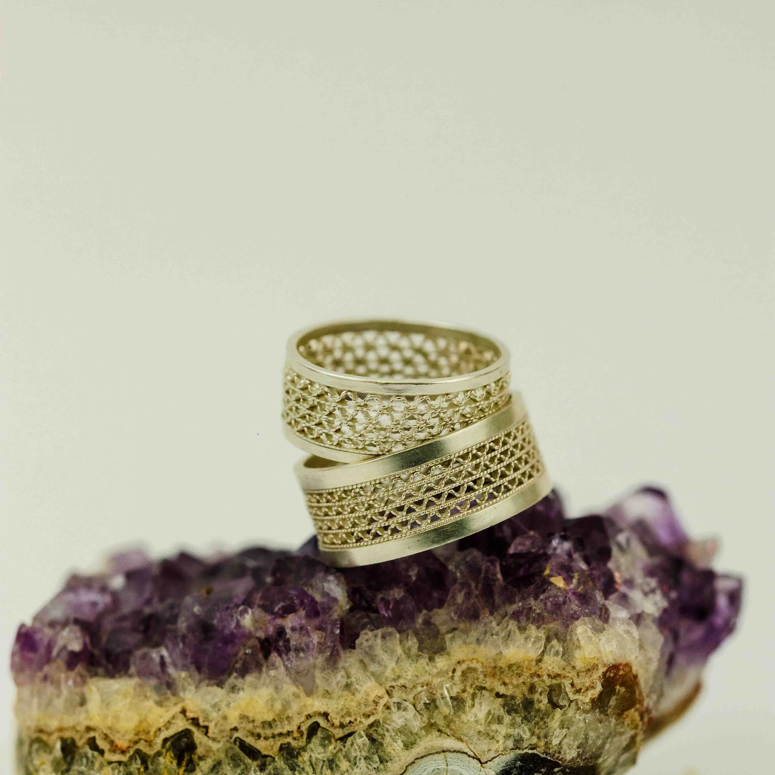 Een ring met een gedetailleerd ontwerp ligt op een stuk boomschors.