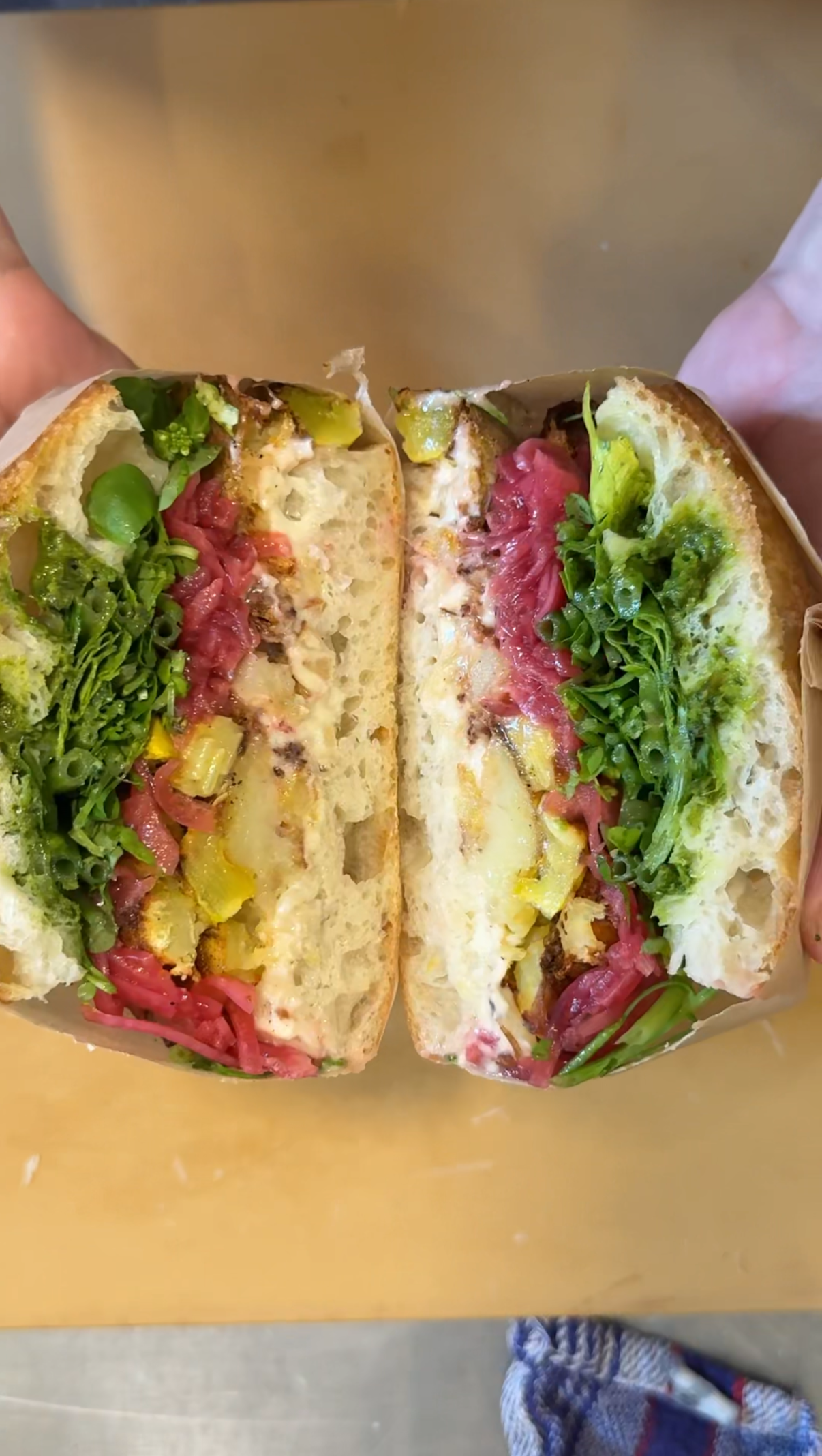 Aufgeschnittenes Sandwich mit Salat, Kartoffeln und anderen frischen Zutaten auf einem Focacciabrot.
