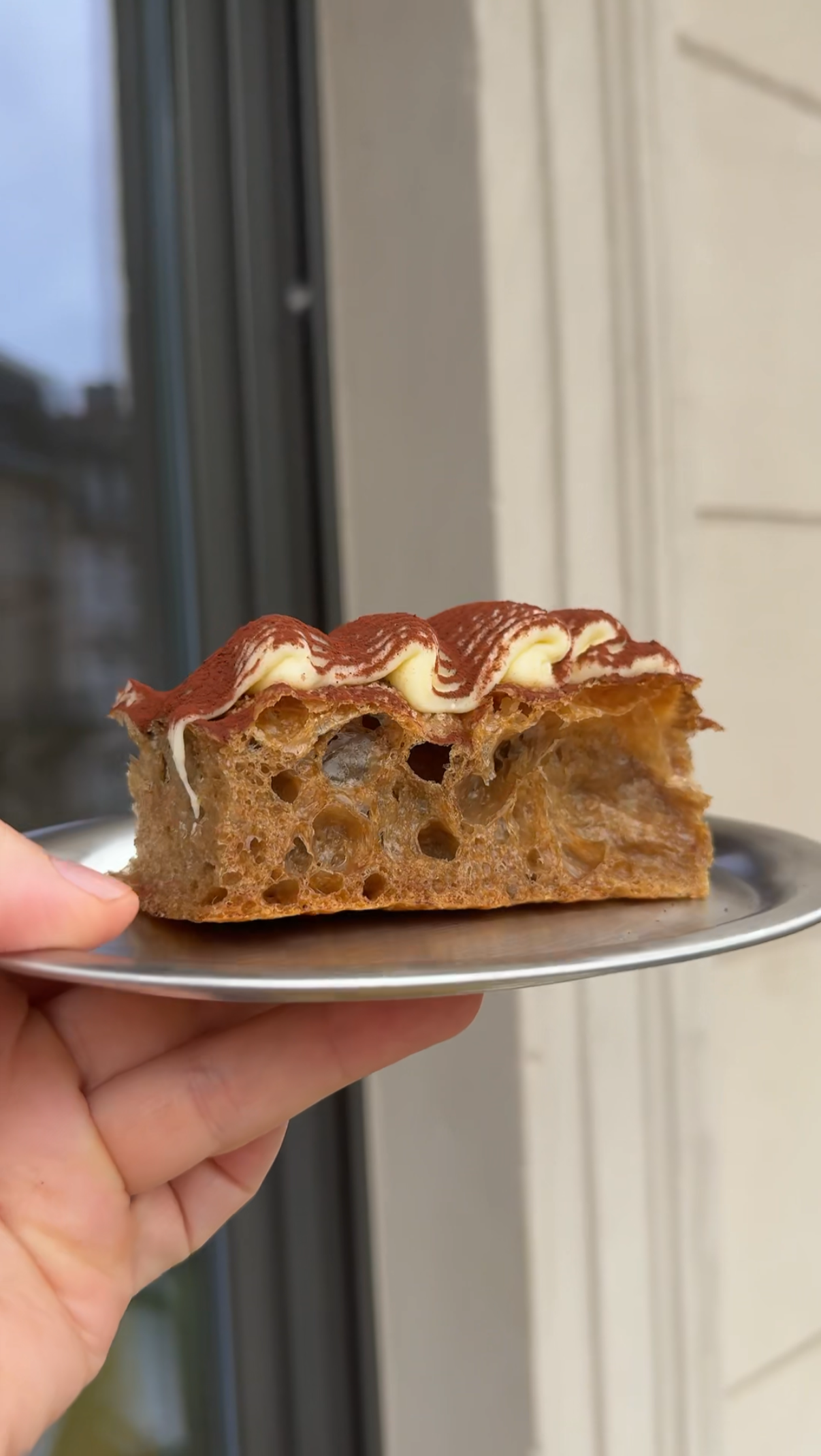 Ein Stück Knuspriges Focaccia-Brot mit einem Belag aus Mascarpone und Kakao auf einem kleinen Teller.