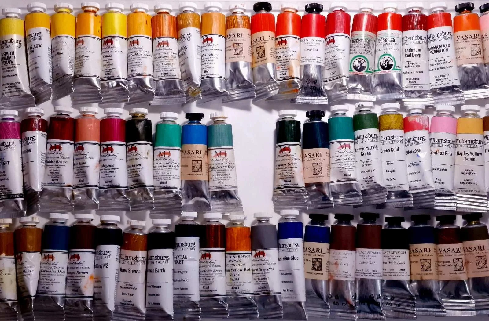 Professional artists’ oil paints arranged around an empty space, reflecting the Material Selection System and the unseen processes that determine which artistic materials remain available.