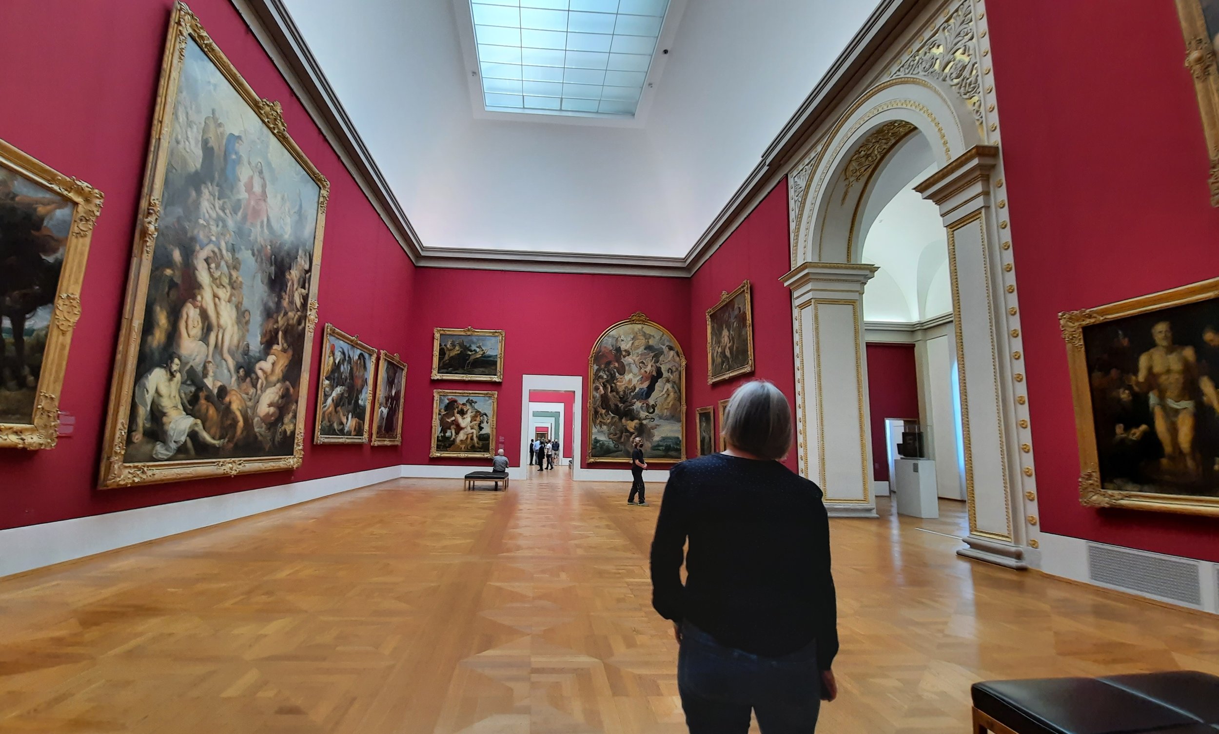 A museum visitor standing before monumental paintings, reflecting on the lasting relationship between people and works of art.