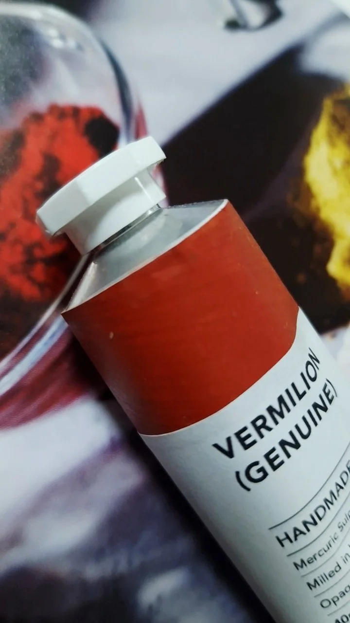 Tube of handmade Genuine Vermilion (PR106) oil paint with historical vermilion pigment in the background, photographed for the Material Memory Project.