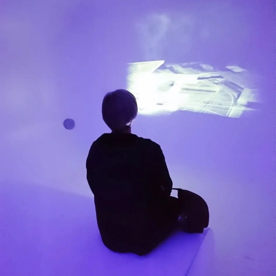 Artist Veronika Kyrychenko observing a projected artwork at Kunstmuseum Den Haag, The Hague.