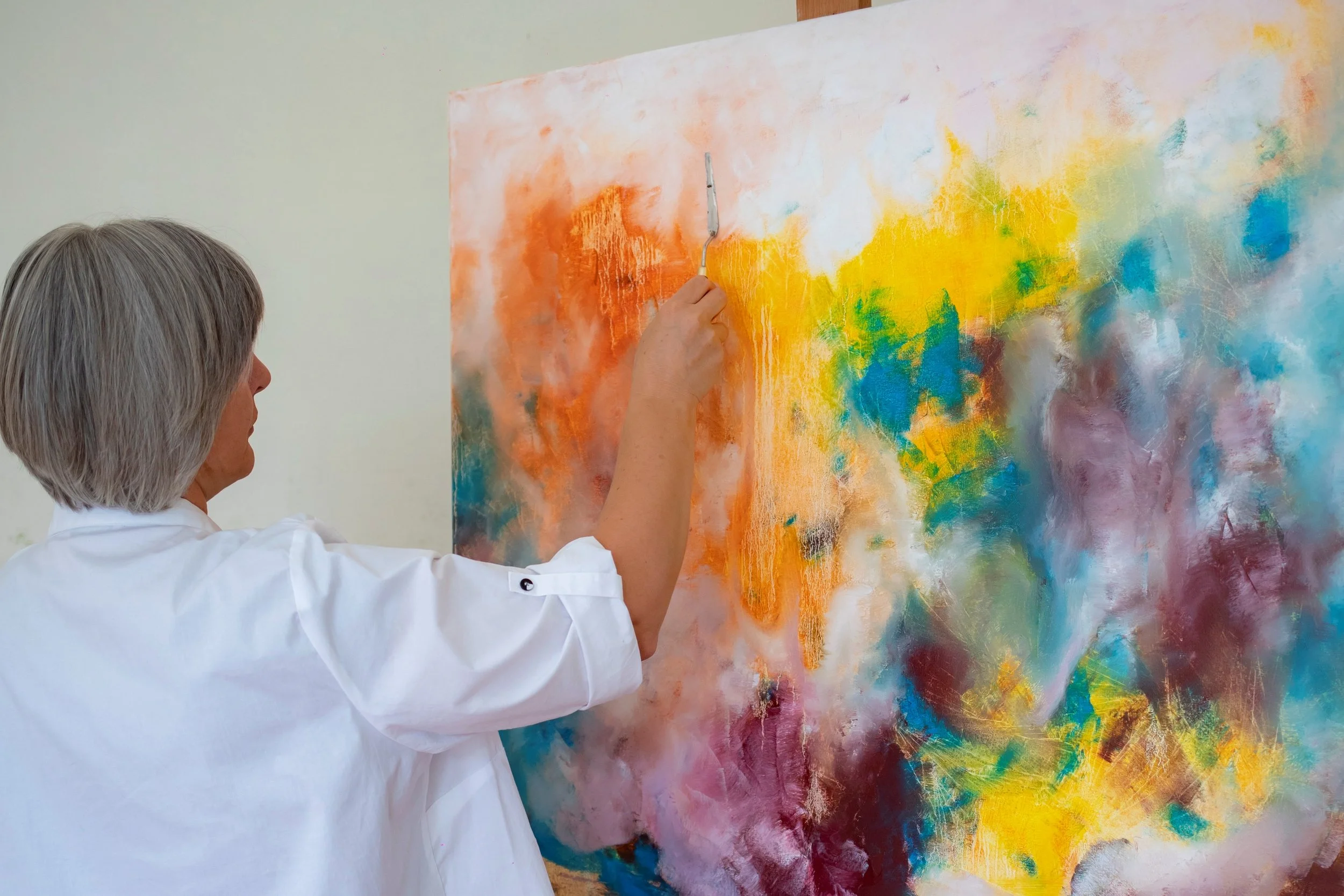 Veronika Kyrychenko working with a palette knife on a large, colourful abstract painting in her studio in Dnipro, Ukraine.