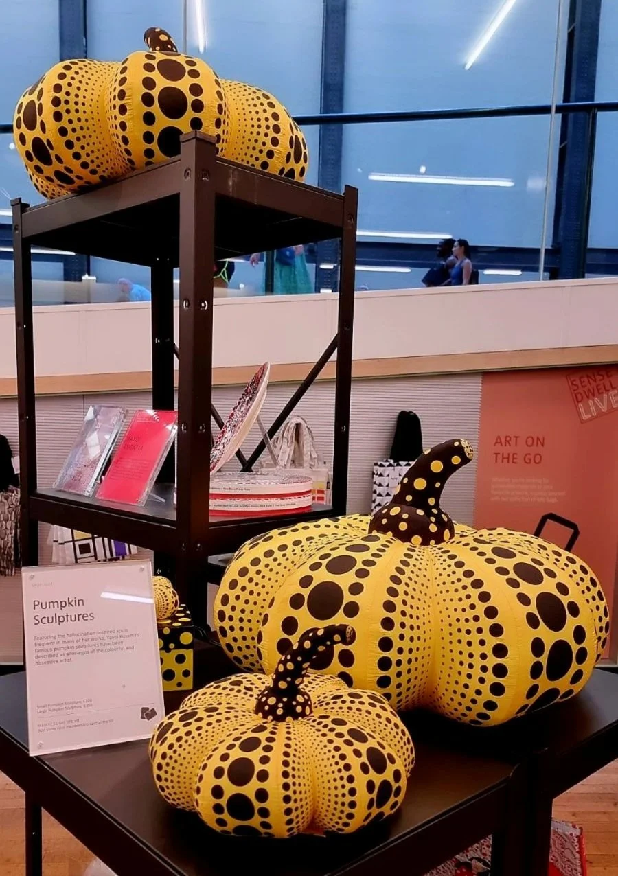 Yayoi Kusama pumpkin sculptures covered in repeating black dots, displayed at a museum shop in 2022.