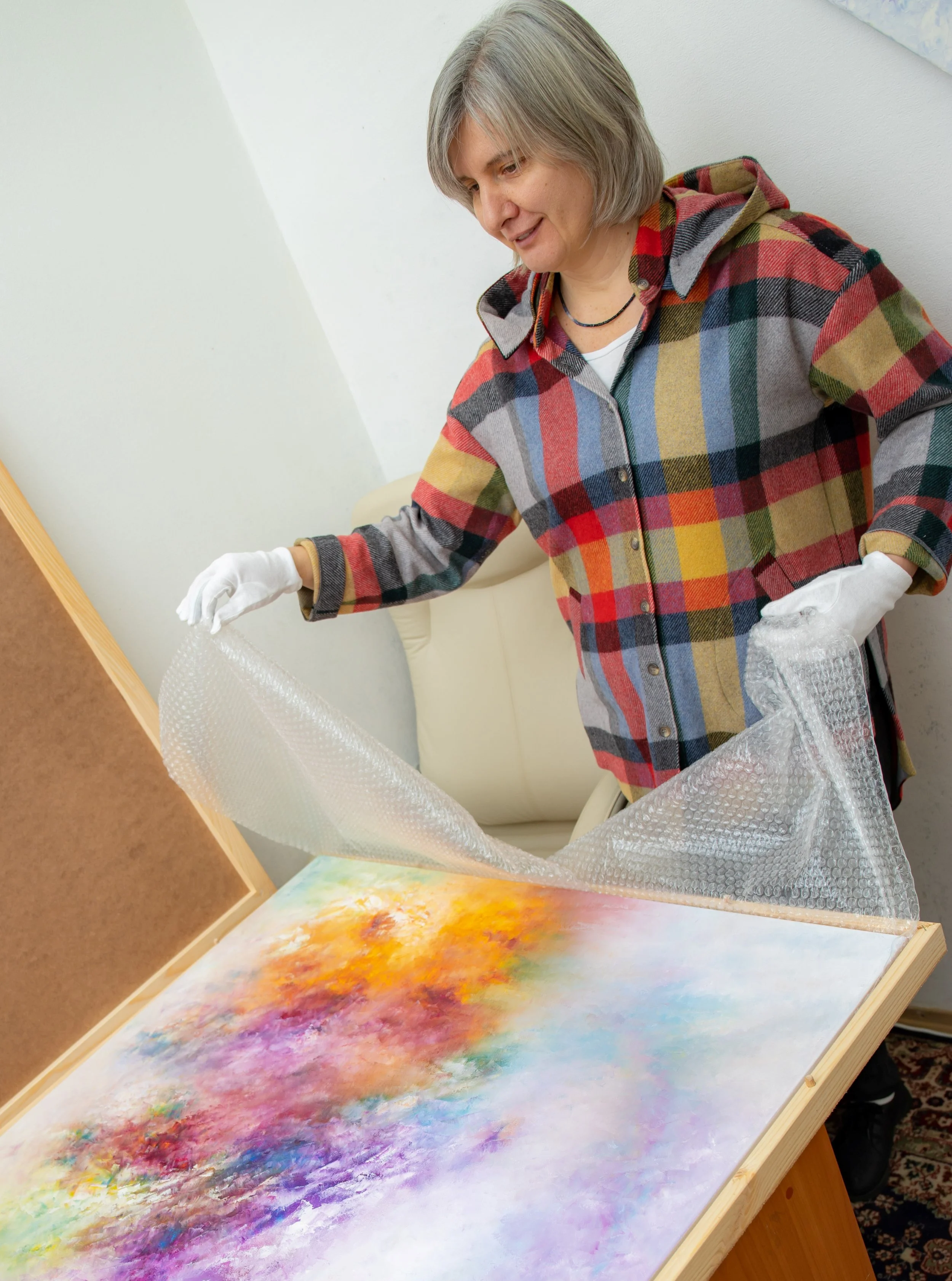 Contemporary artist Veronika Kyrychenko carefully packing an original oil painting in her studio before shipping to a collector.