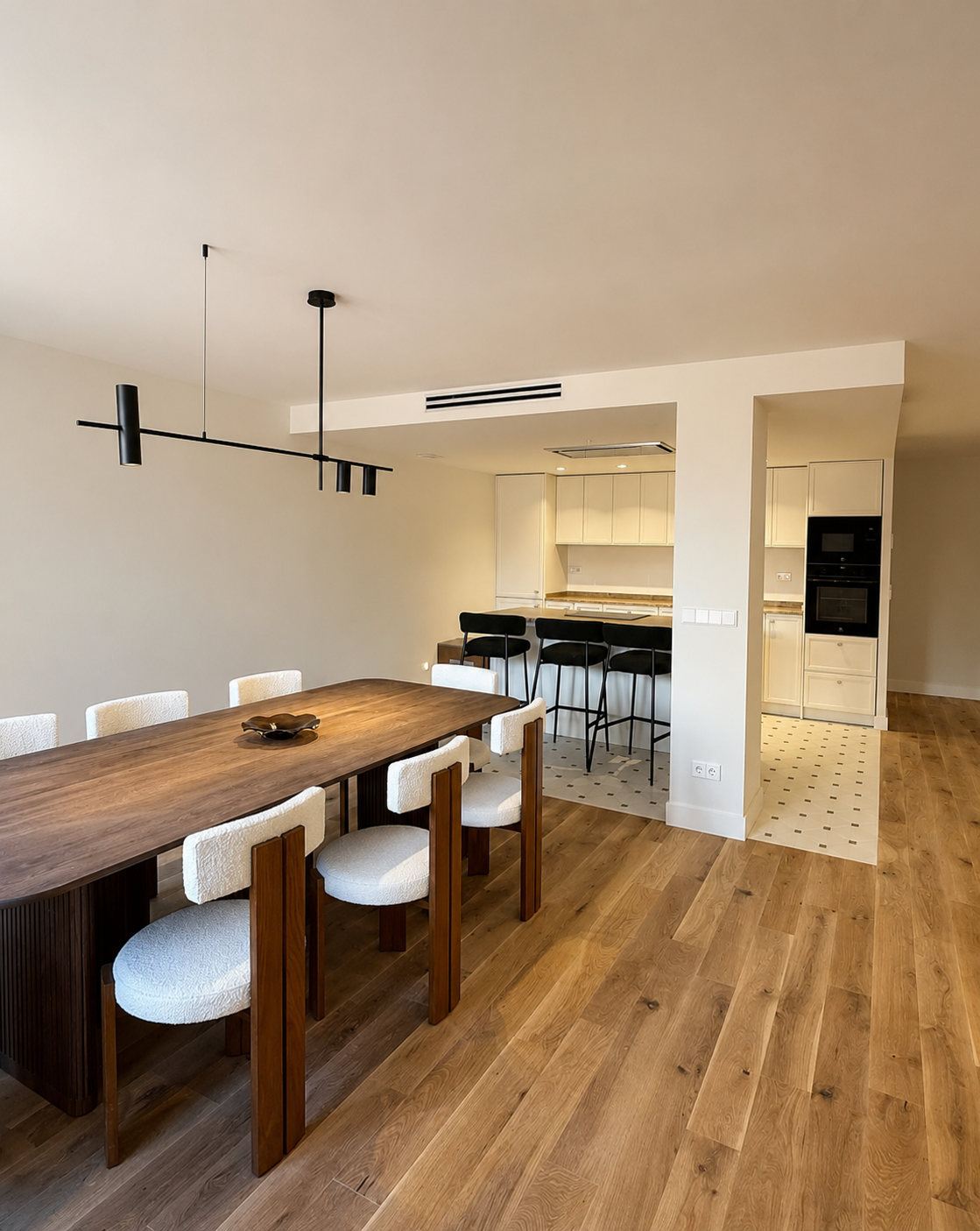 Reforma de vivienda con cocina abierta, isla central, comedor integrado y materiales cálidos.
