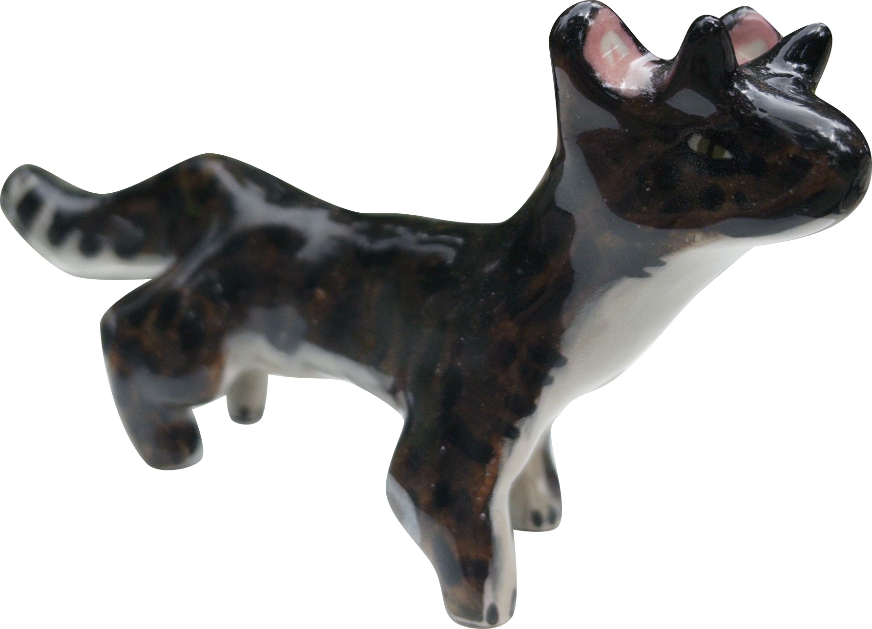 A ceramic figurine of a black and white cow lying down, facing to the right.