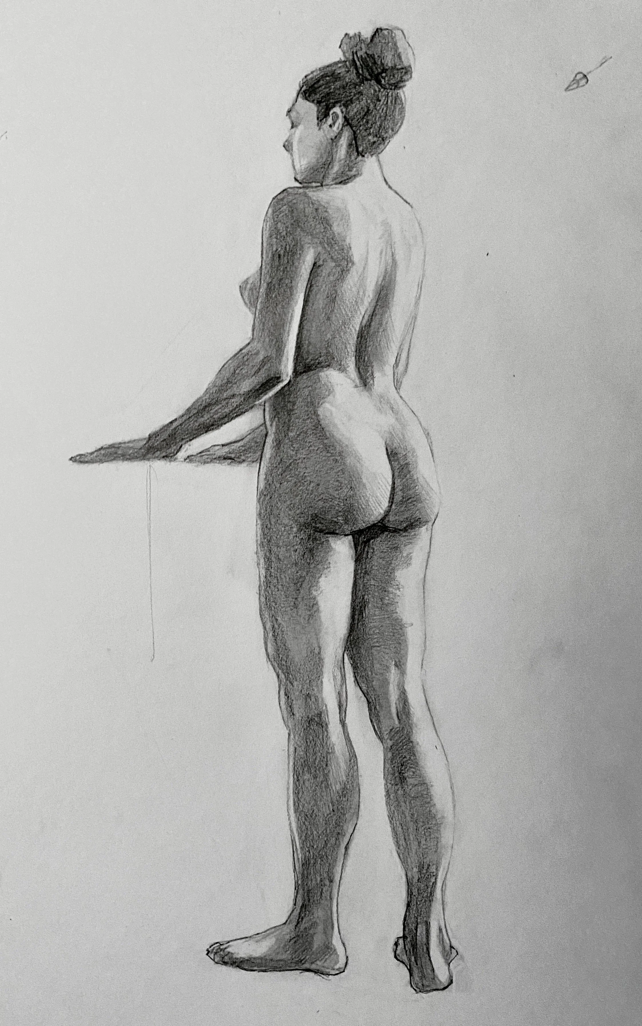 A realistic pencil sketch of a nude woman standing with her back facing the viewer, her hair in a bun, holding a surface with one arm, in a side view.