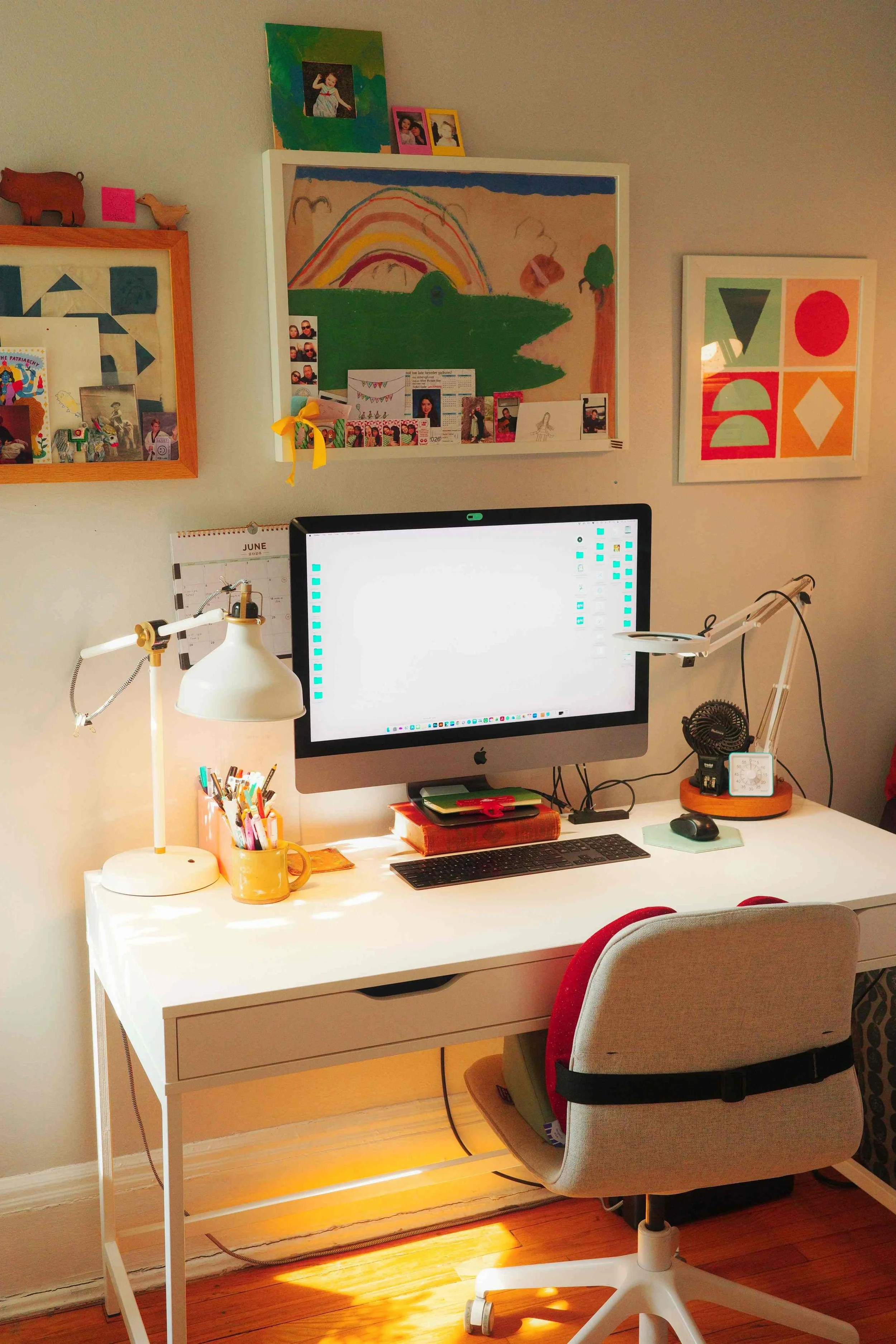Desk and shelves in Denise Holmes’ illustration studio with books, artwork, and tools used for creating children’s books.