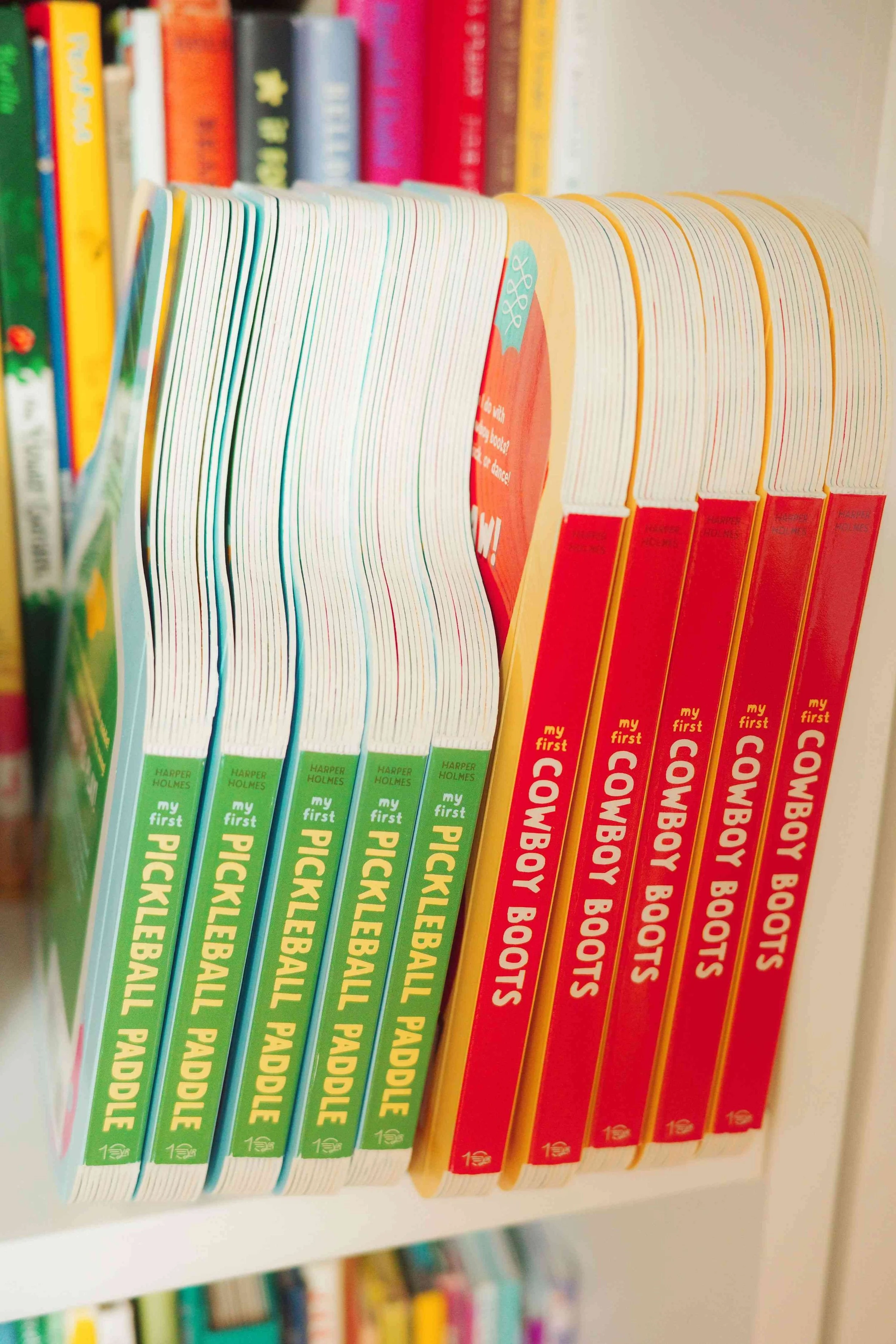 Shelf of Denise Holmes’ illustrated board books, including My First Pickleball Paddle and My First Cowboy Boots.