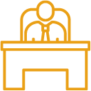 Icon of a person sitting at a desk, facing forward.