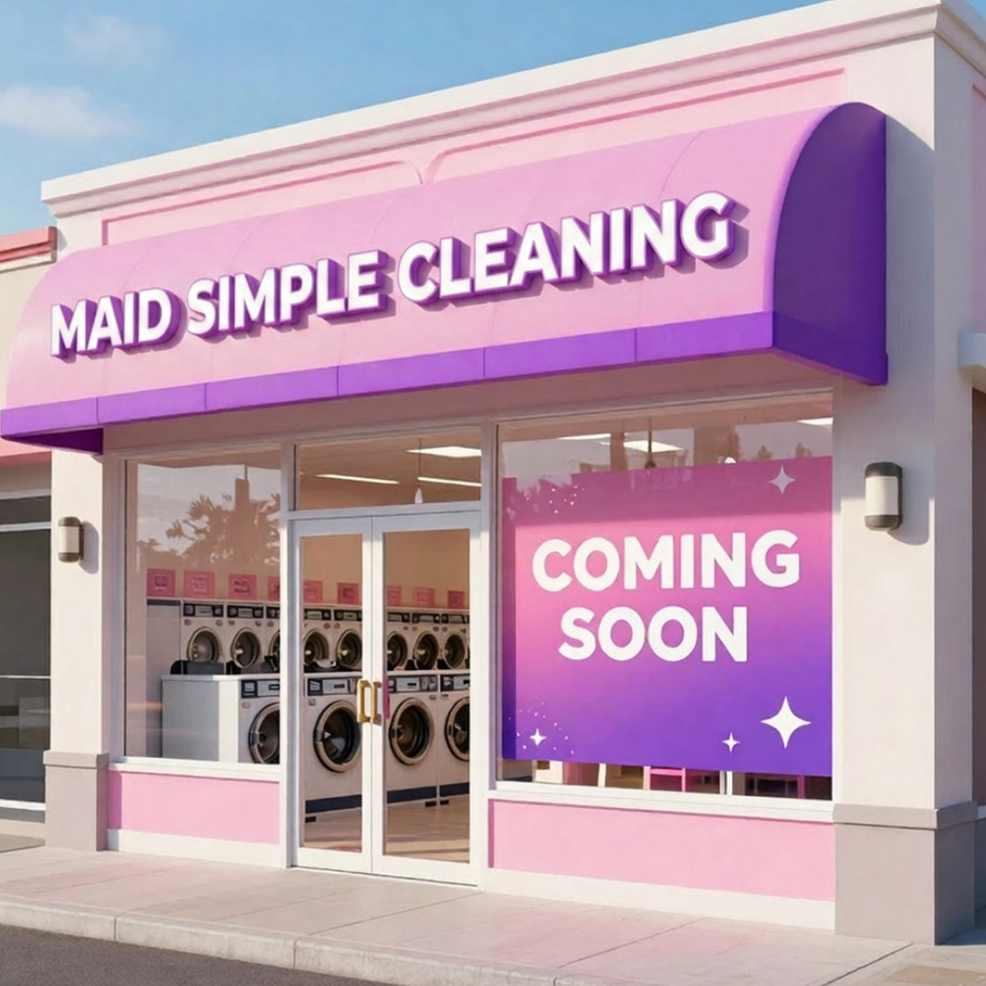 New laundromat named Maid Simple Cleaning with pink and purple signage, large window, and washing machines visible inside, and a sign indicating it is opening soon.