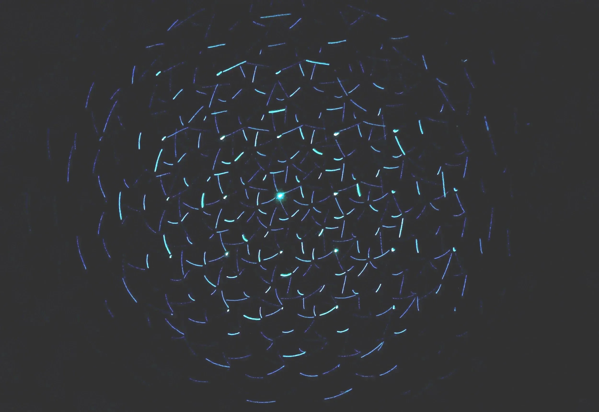 Dark image with faint glowing blue lines forming a circular, spiral, or net-like pattern.