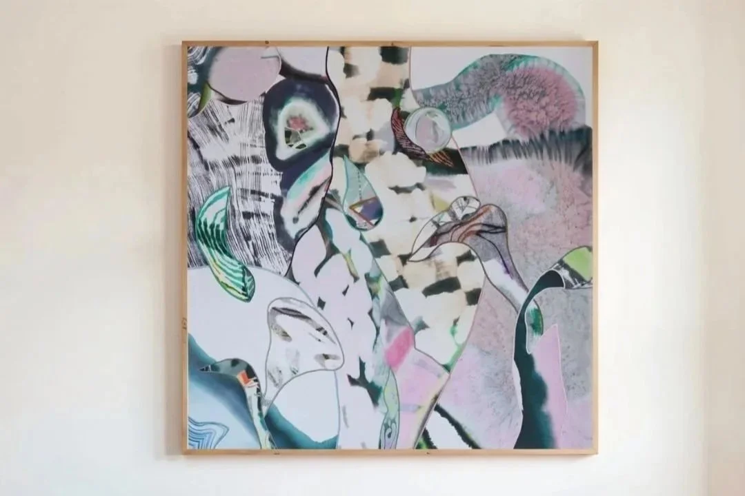 Abstract artwork with various colors, shapes, and patterns, framed on a wall.