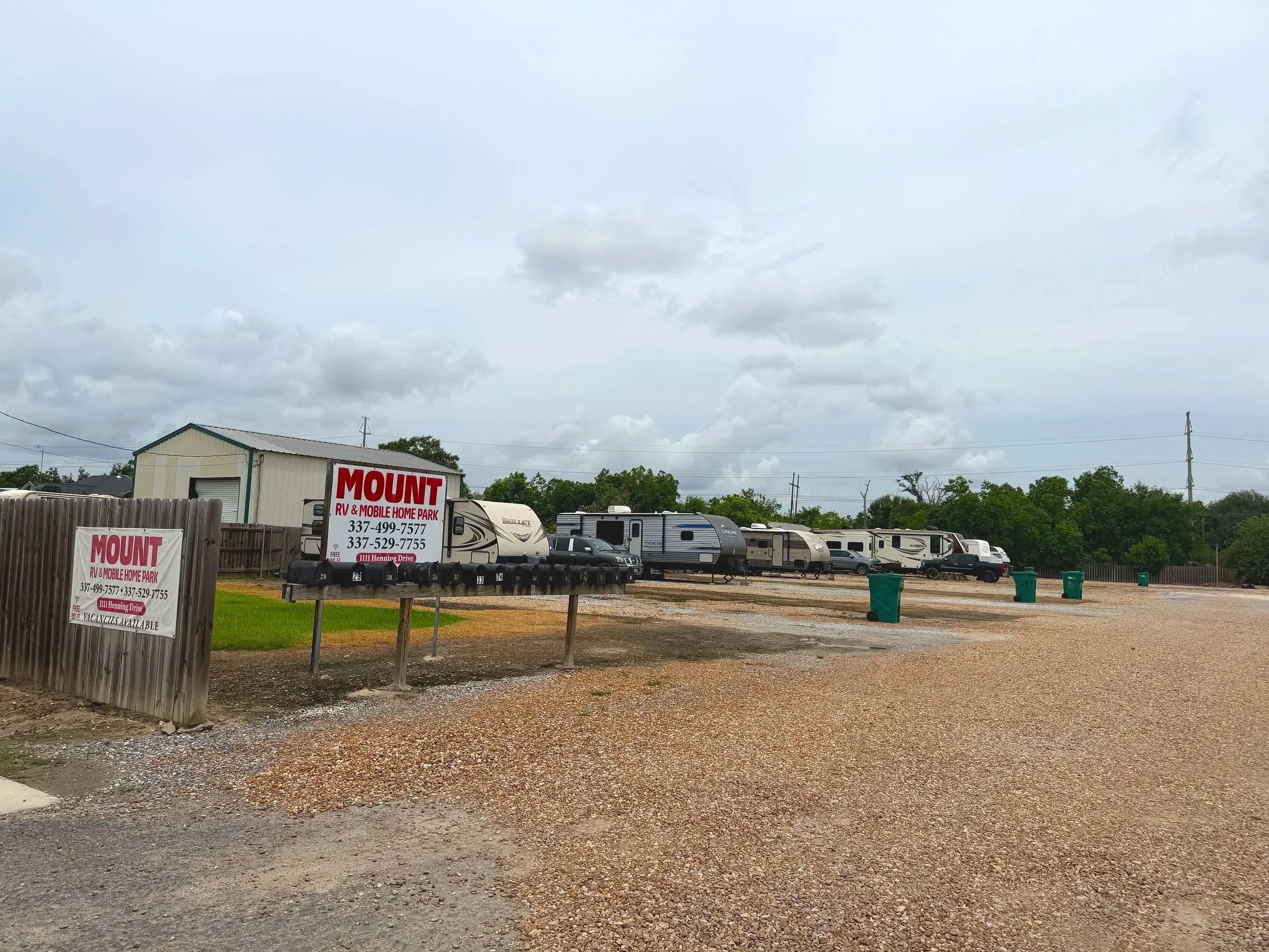 A parking lot filled with RVs and campers under a cloudy sky, with a sign advertising Mount RV and Mobile Home Park in the foreground.