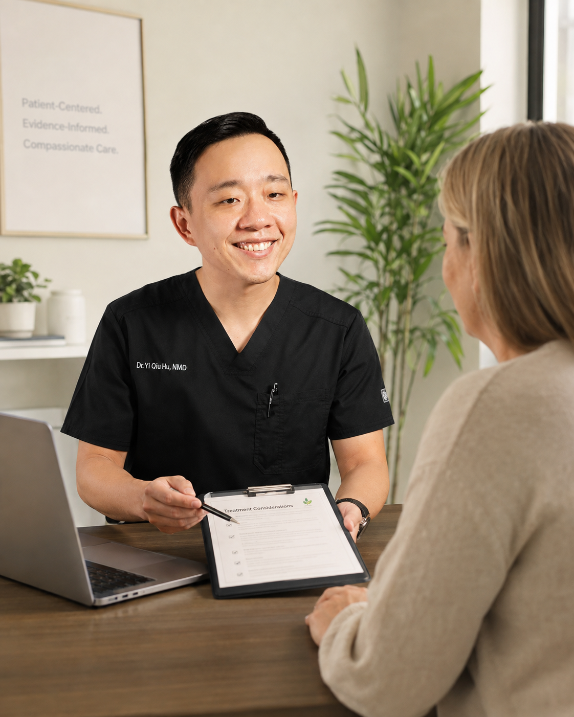 A doctor in a black medical uniform sitting at a desk, smiling and talking with a female patient. The doctor holds a clipboard with a document titled 'Treatment Considerations'. There is a laptop on the desk and a plant in the background.