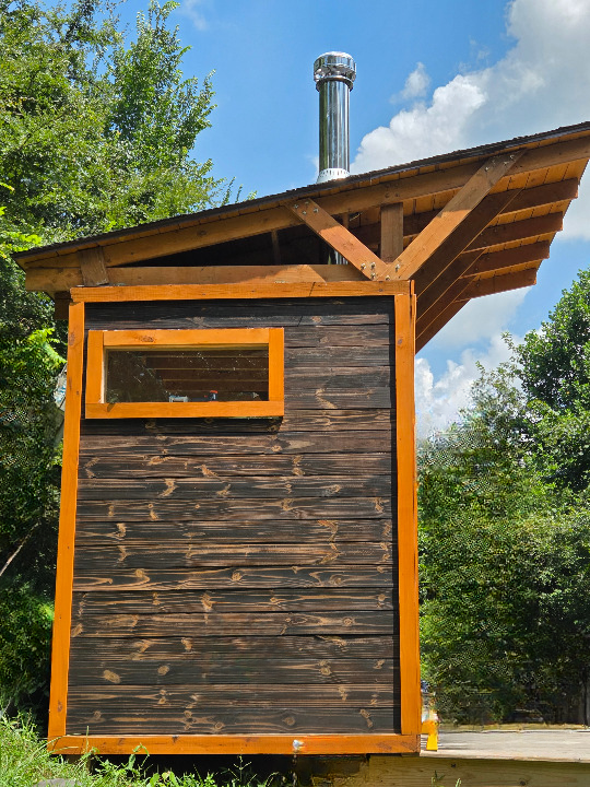 Outdoor wood-burning sauna situated in the remote woods.