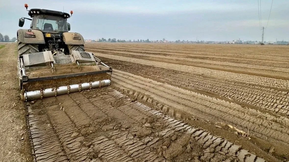 Un trattore sta arando un campo di terra.