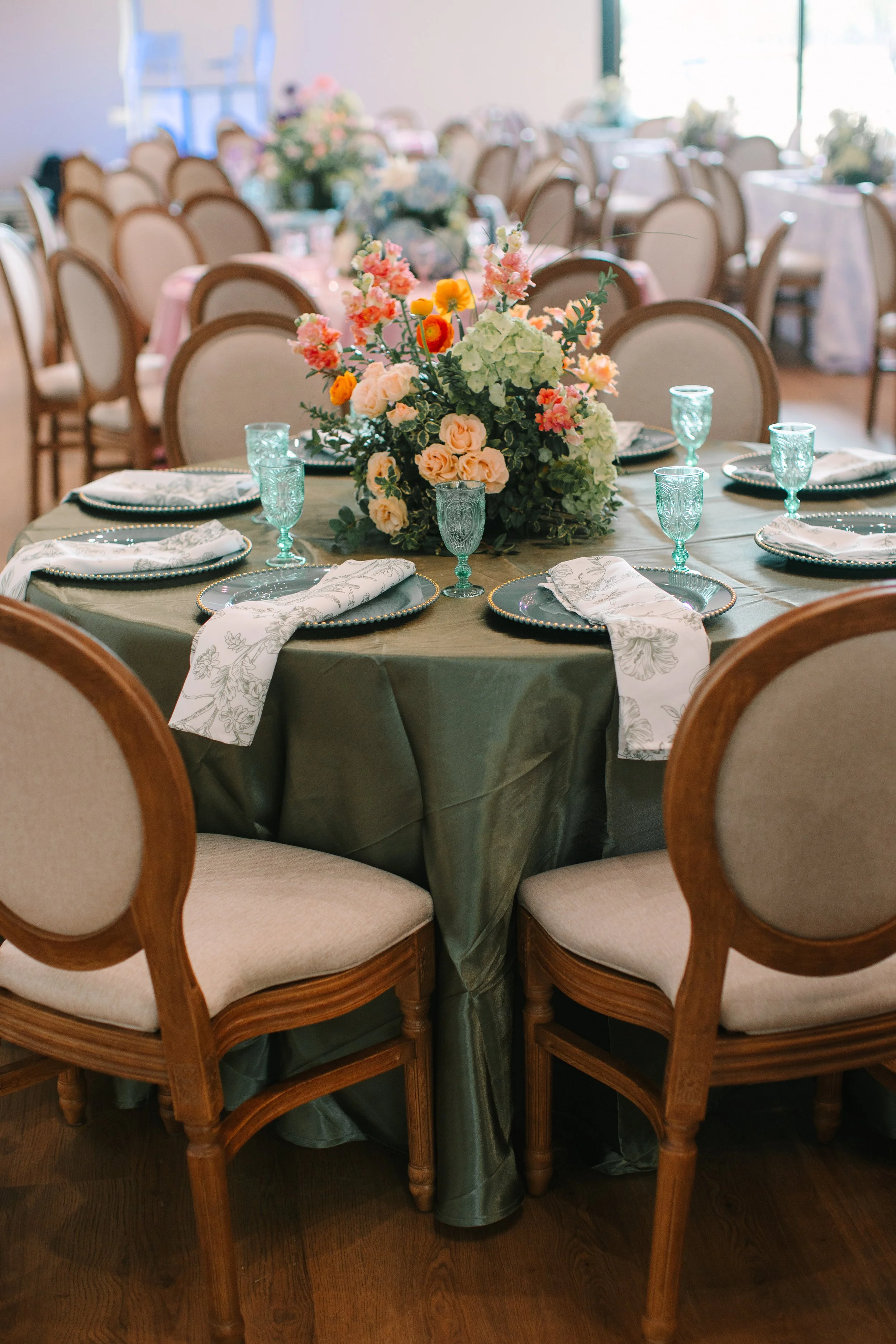 wedding reception Round table set with floral centerpiece, glasses, plates, and napkins in a decorated dining room.