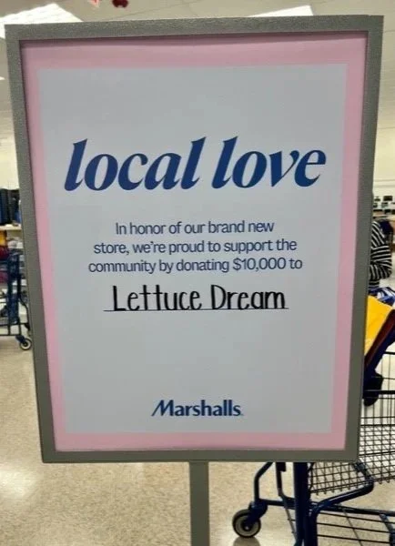 Rectangle sign in blue font reads "local love in honor of our brand new store, we're proud to support the community by donating $10,000 to Lettuce Dream" Marshalls