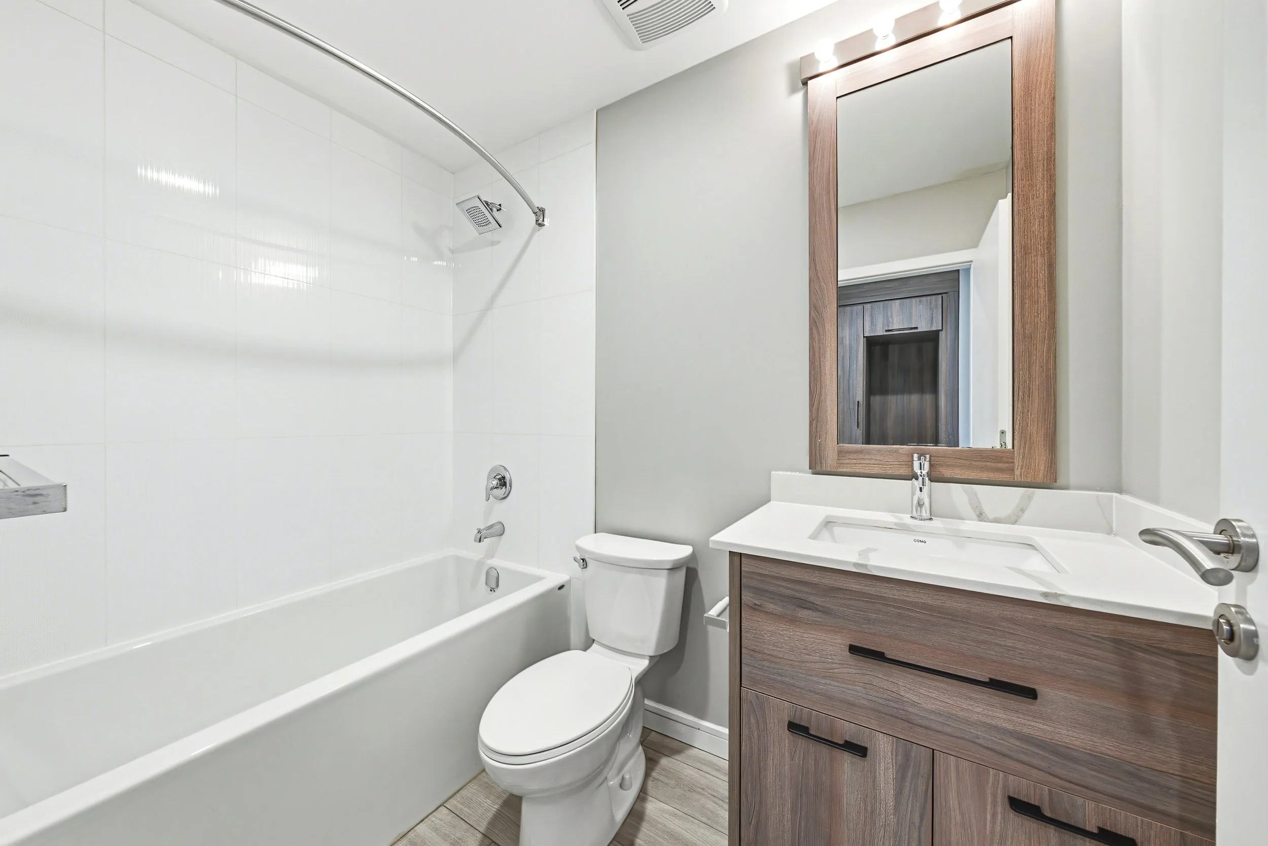 Modern bathroom with a bathtub, shower, toilet, and vanity with mirror.