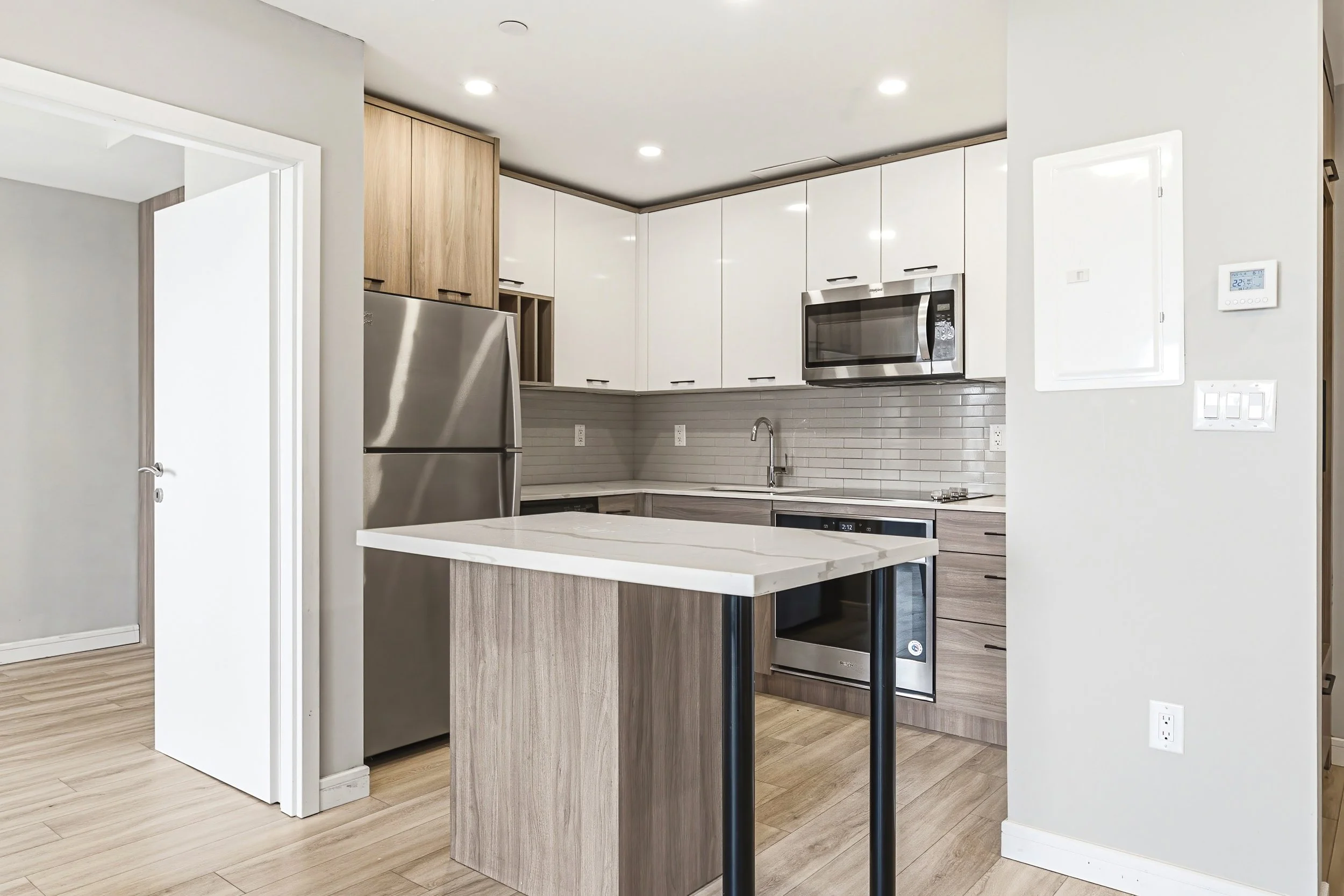 Modern kitchen with white cabinets, stainless steel appliances, and a kitchen island with a white marble countertop.
