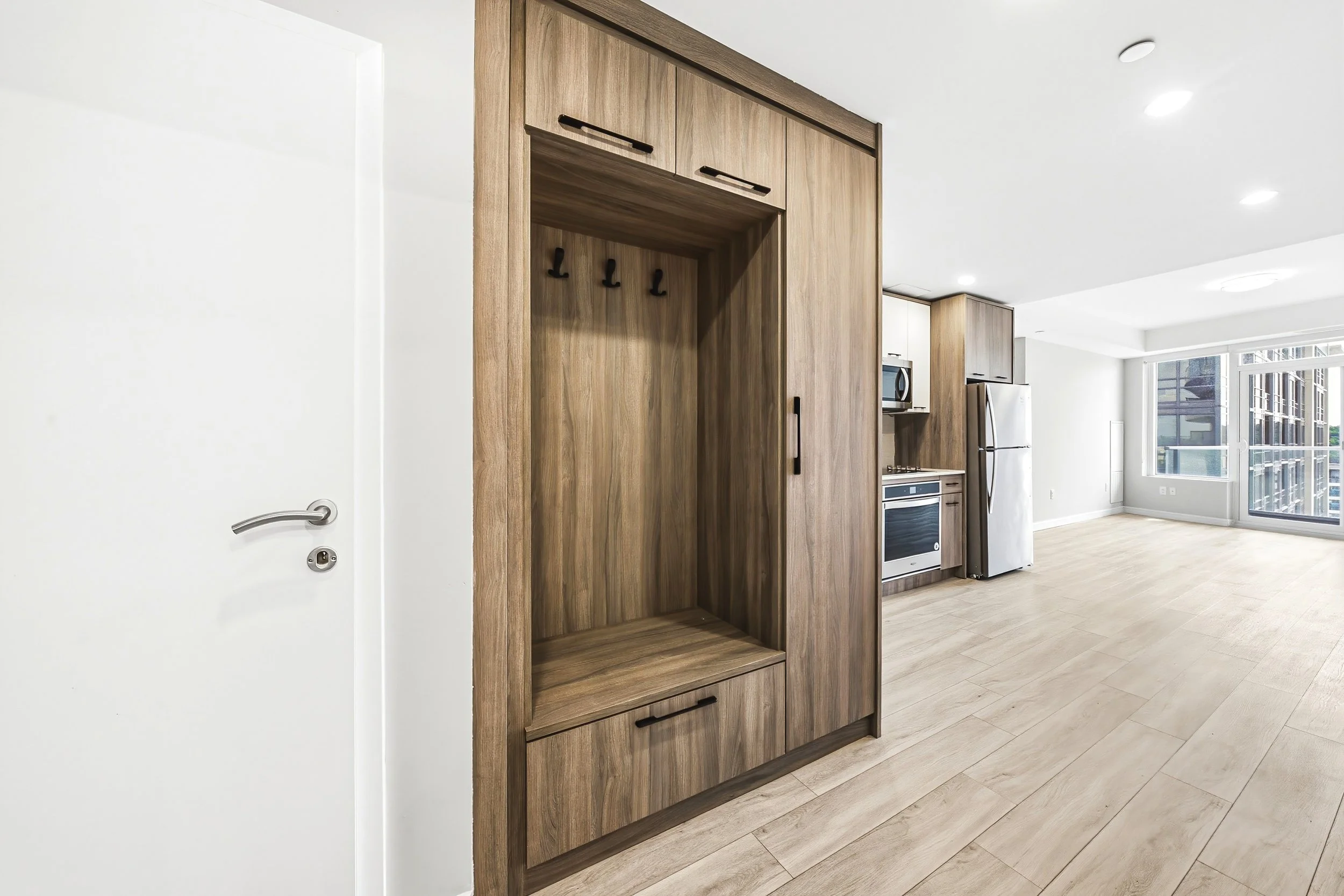 Modern kitchen with white walls, wooden cabinetry, and large window providing natural light.