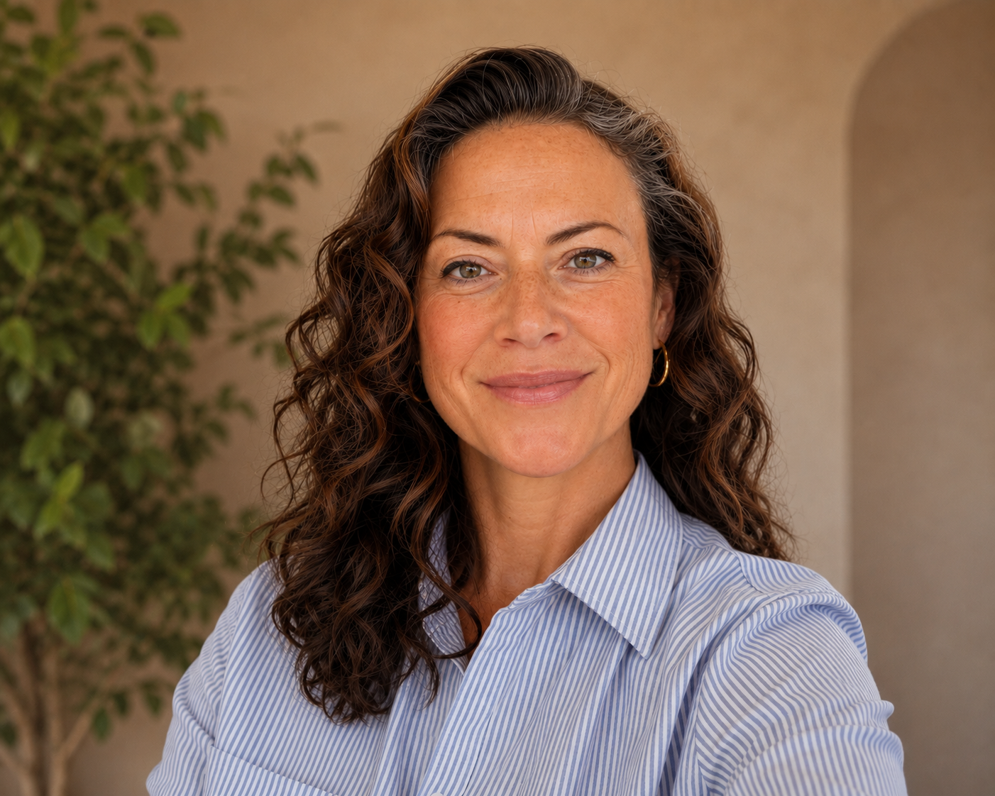 Chrystal Nelthropp, LPC, LMHC at Holistic Northwest. Providing therapy for women in-person in Manzanita Oregon, and online throughout OR & WA. With brown and grey hair, wearing a blue striped shirt and smiling with kind eyes.