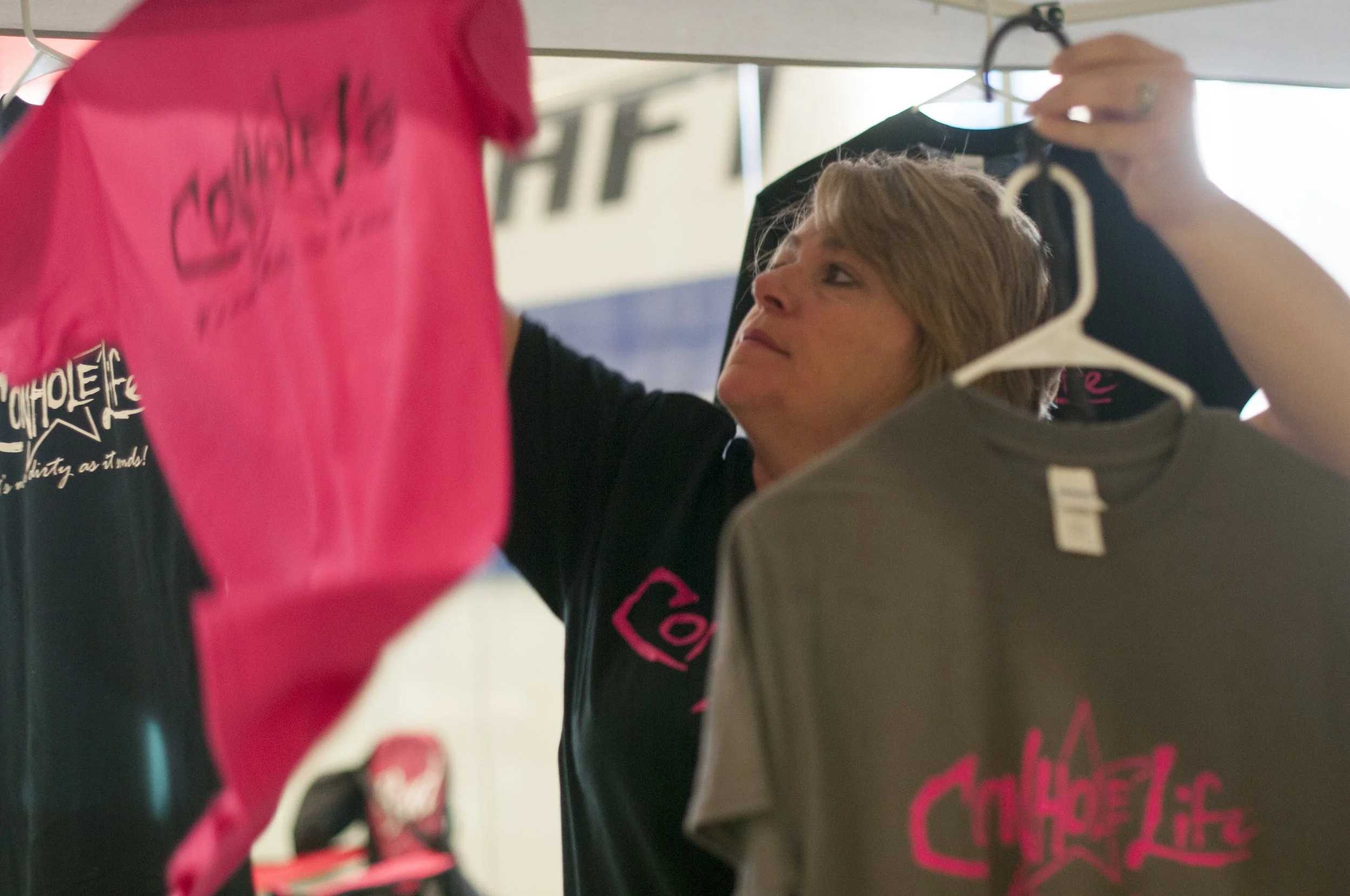 Kim Howard, co-founder of Cornhole Life, hangs t-shirts in their vendor tent at the ACO Majors, Season X, Virginia Beach, Virginia, April 18, 2015.