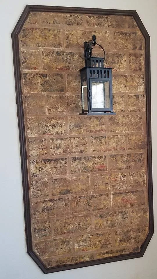 False Wall:
That's not brick. It's acrylic paint on a plain wood panel, and the lantern's the only real thing in the shot.