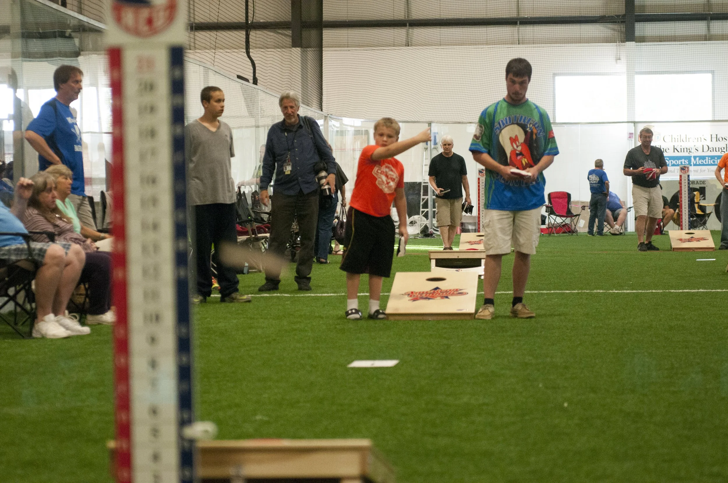 Bobby Morris, Jr. throws a bag as his competitor, Caleb Avery, looks on at the ACO Majors, Season X, Virginia Beach, Virginia, April 17, 2015. Morris and Avery were competing in the junior's category.