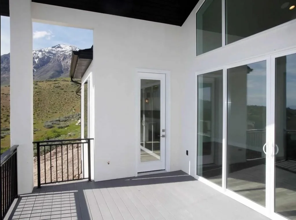 A balcony with glass sliding doors and a view of snow-capped mountains and desert landscape.