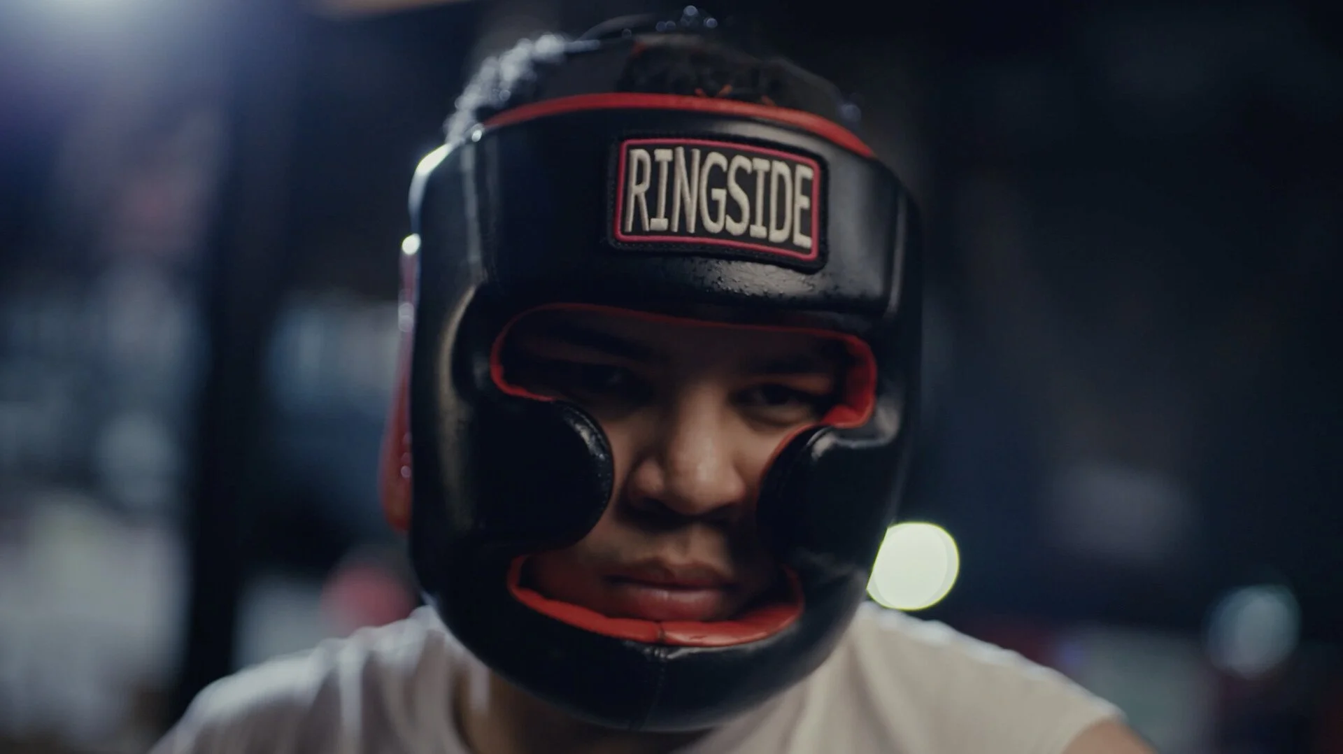 Close-up of a young boxer wearing a protective headgear with the logo 'RINGSIDE' and a confident expression.