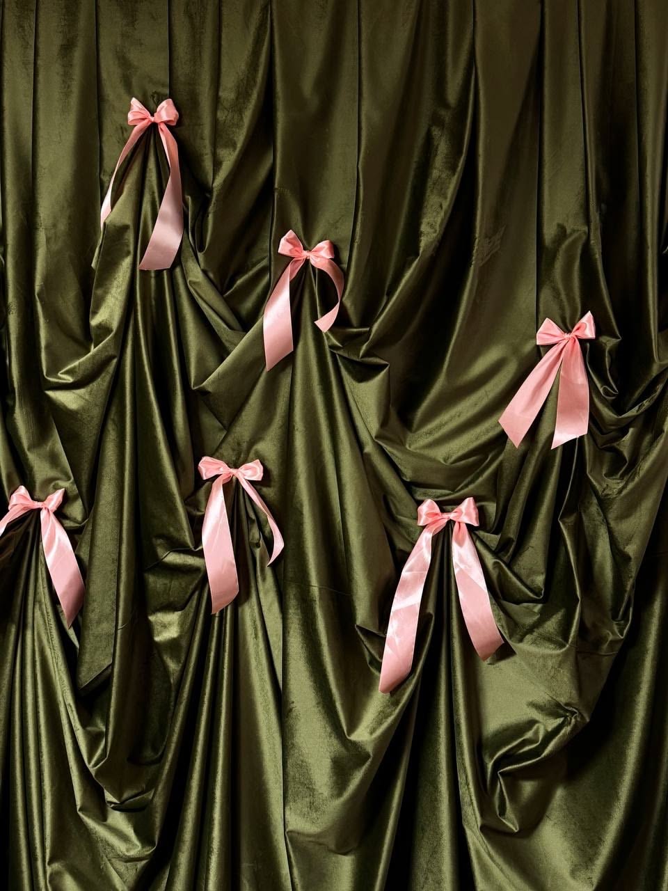 Green satin fabric backdrop decorated with pink satin bows.