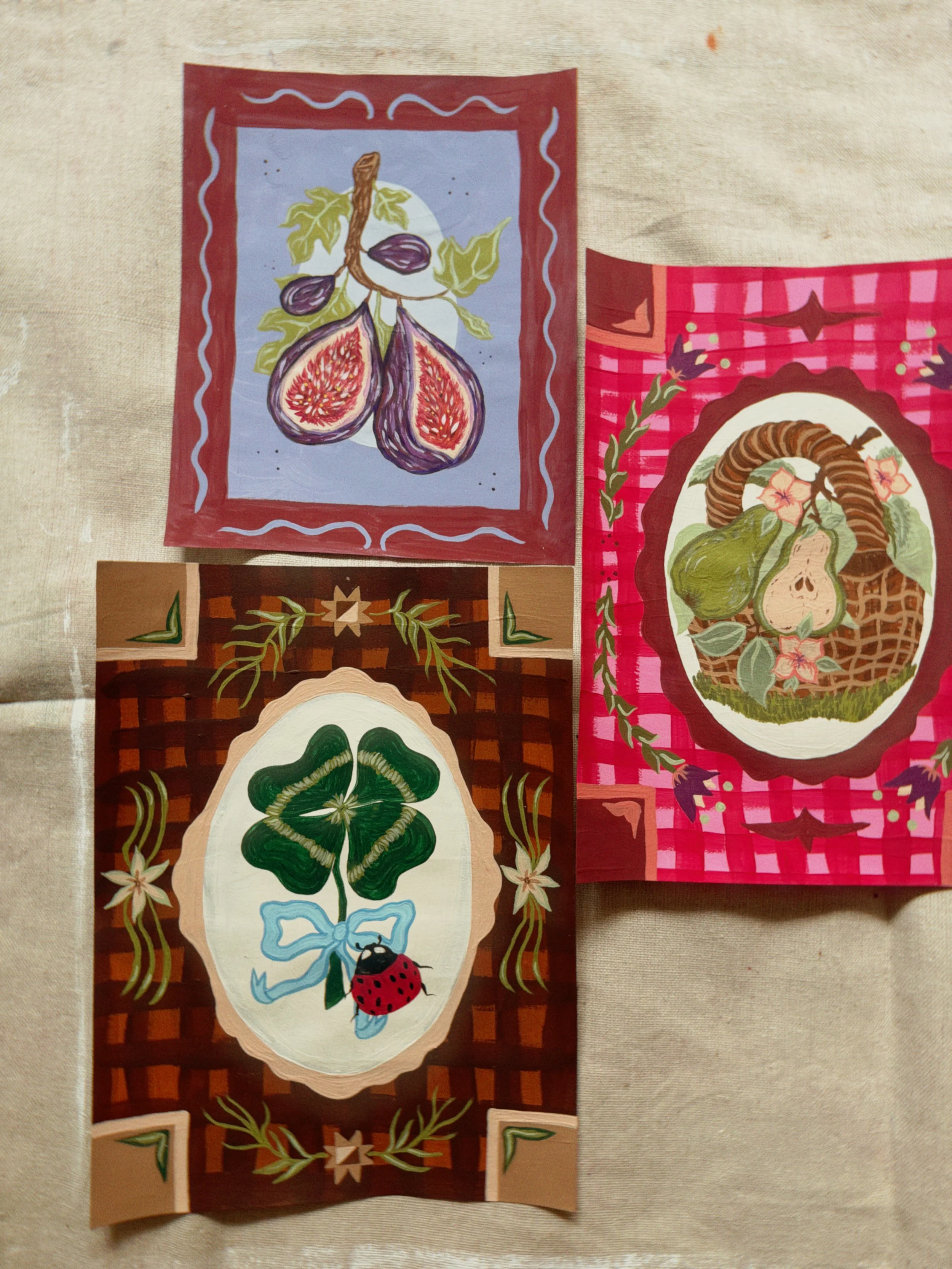 Colorful fabric pieces with botanical and fruit illustrations, including figs, green leaves, and a ladybug on a white background, bordered with decorative patterns.