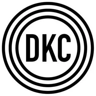 Black and white circular logo with the letters DKC in the center surrounded by concentric circles.