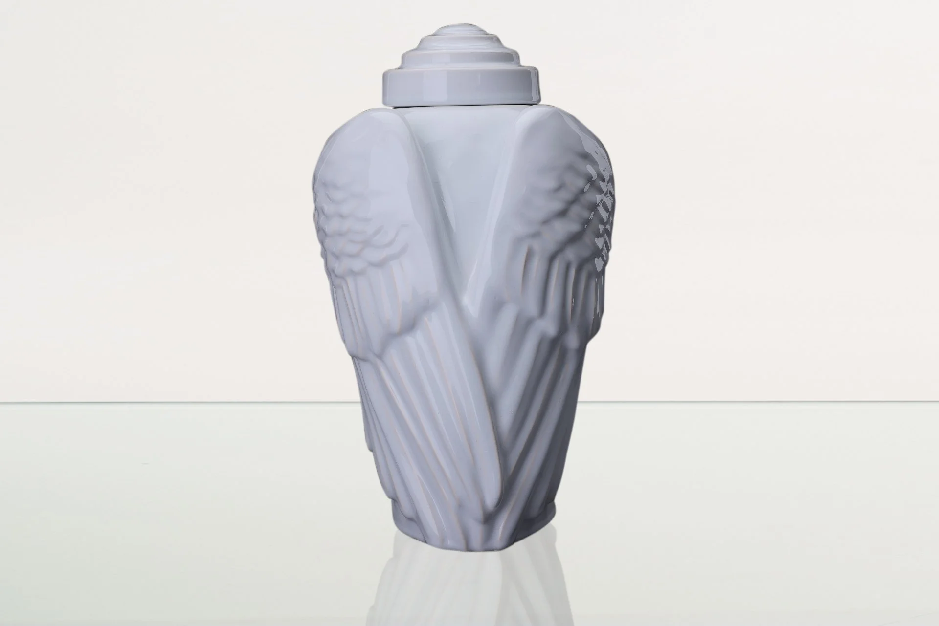 Detail keramické urny Wings s jemně tvarovaným designem připomínajícím křídla.
