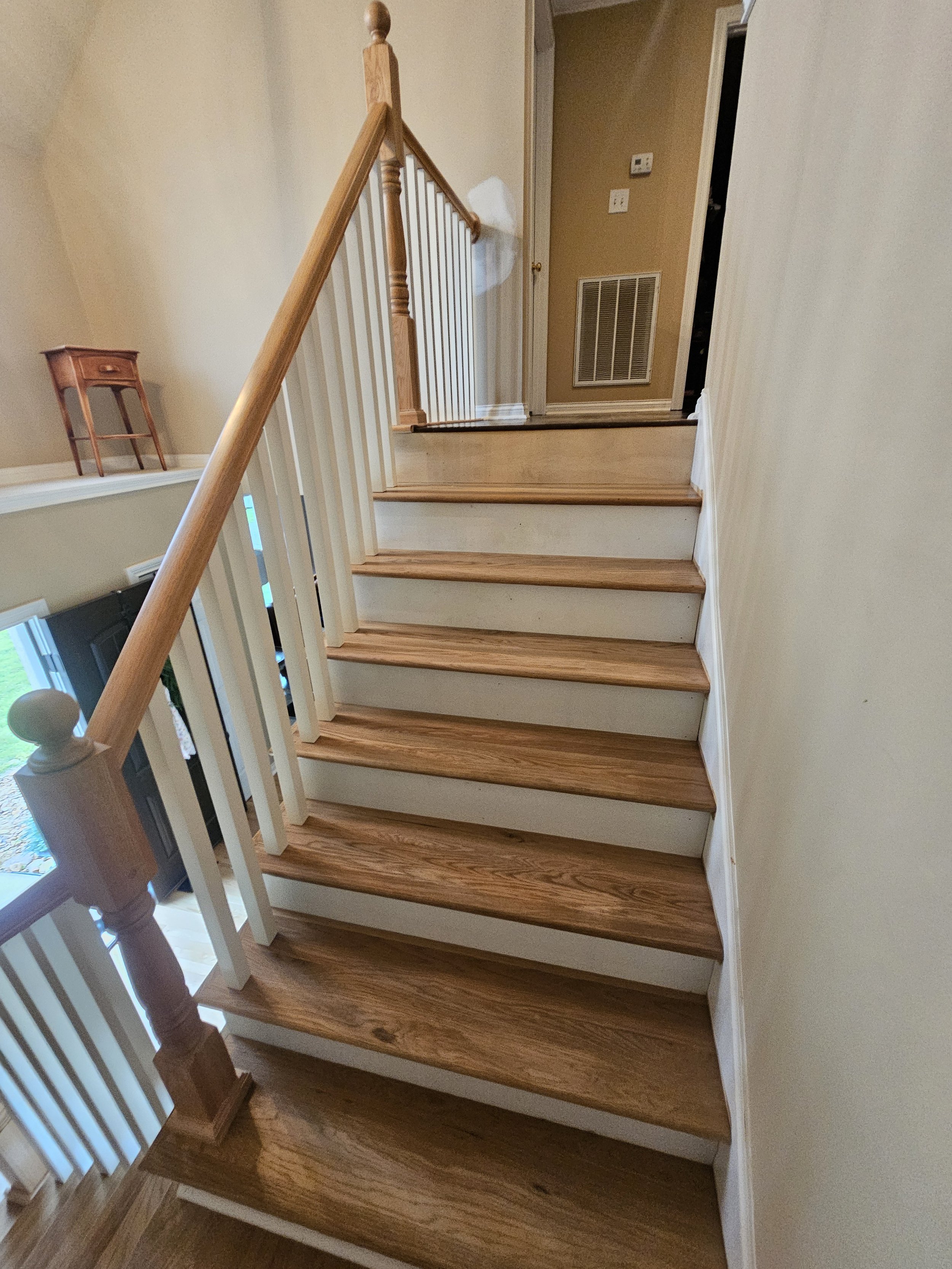 Wooden staircase with white risers leading to an upper floor in a house interior.