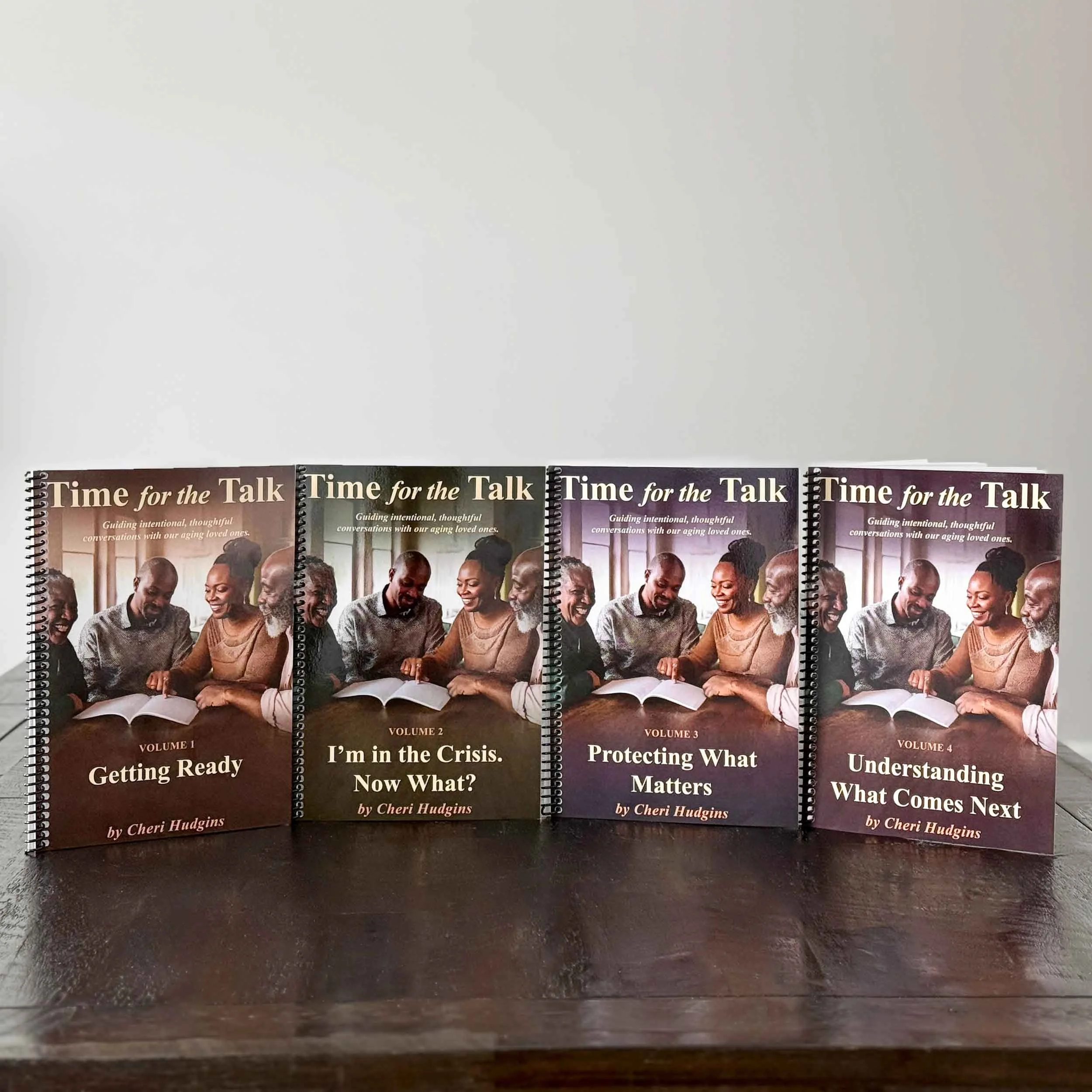 Set of four spiral-bound books titled 'Time for the Talk' by Cheri Hudgins, featuring images of diverse older adults sharing stories and laughter, on a dark wooden surface.