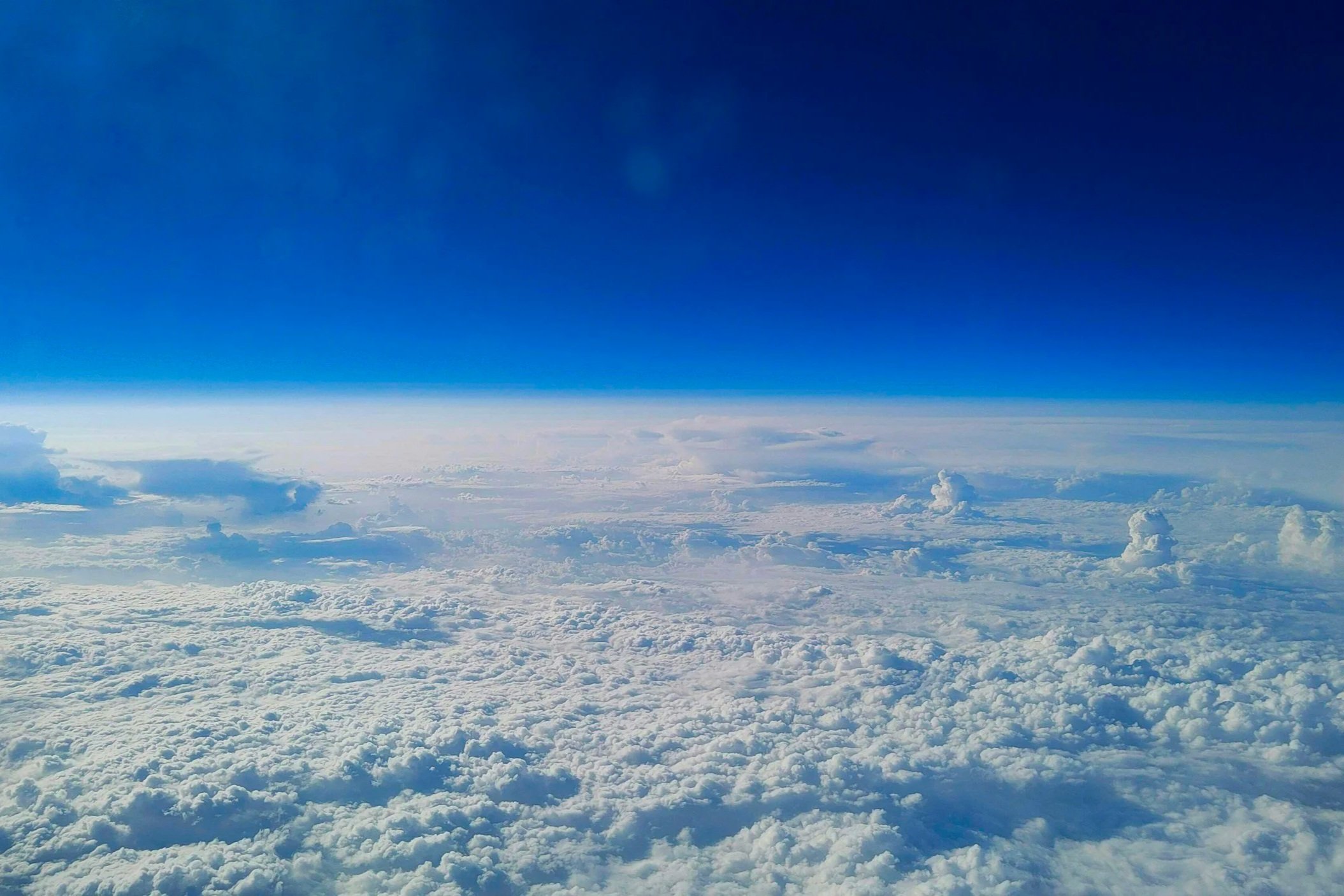 View of a sky from space filled with clouds and a clear blue sky above.